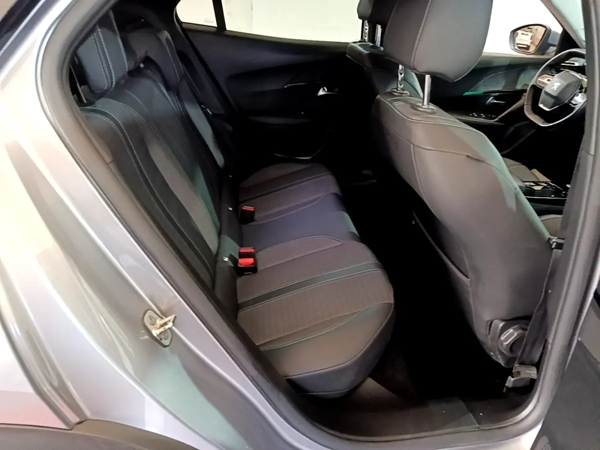 Vue intérieure côté gauche arrière du Peugeot 2008 gris clair, montrant la banquette arrière et partie avant cuir noir.