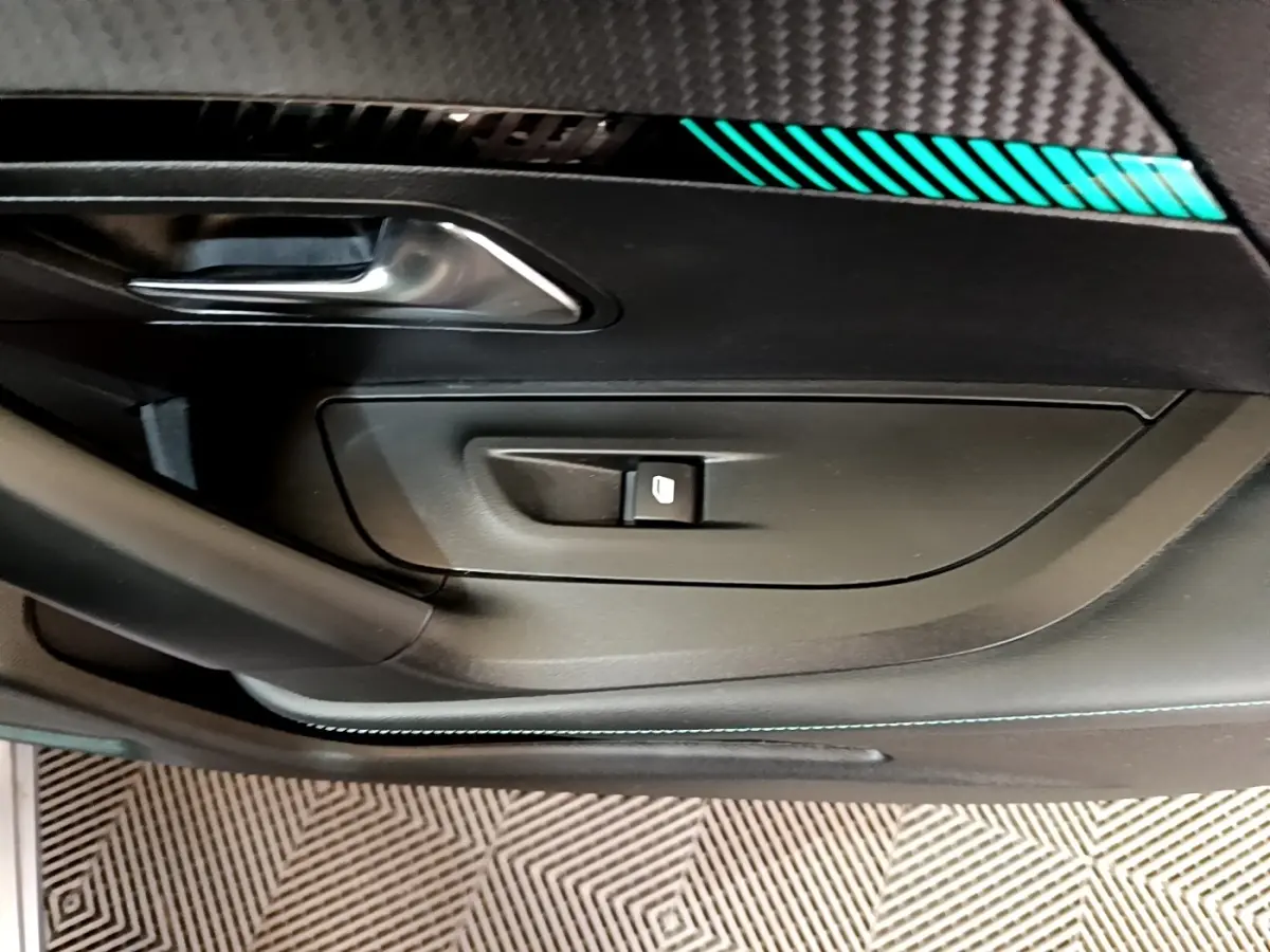 Gros plan sur la porte intérieure côté gauche du Peugeot 2008 gris clair, avec poignée argentée et commande de vitre.