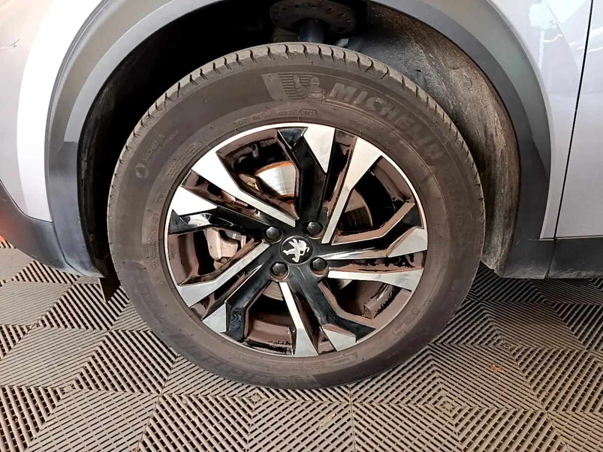 Gros plan sur la roue avant gauche gris clair du Peugeot 2008 avec jante alliage noire et argentée.