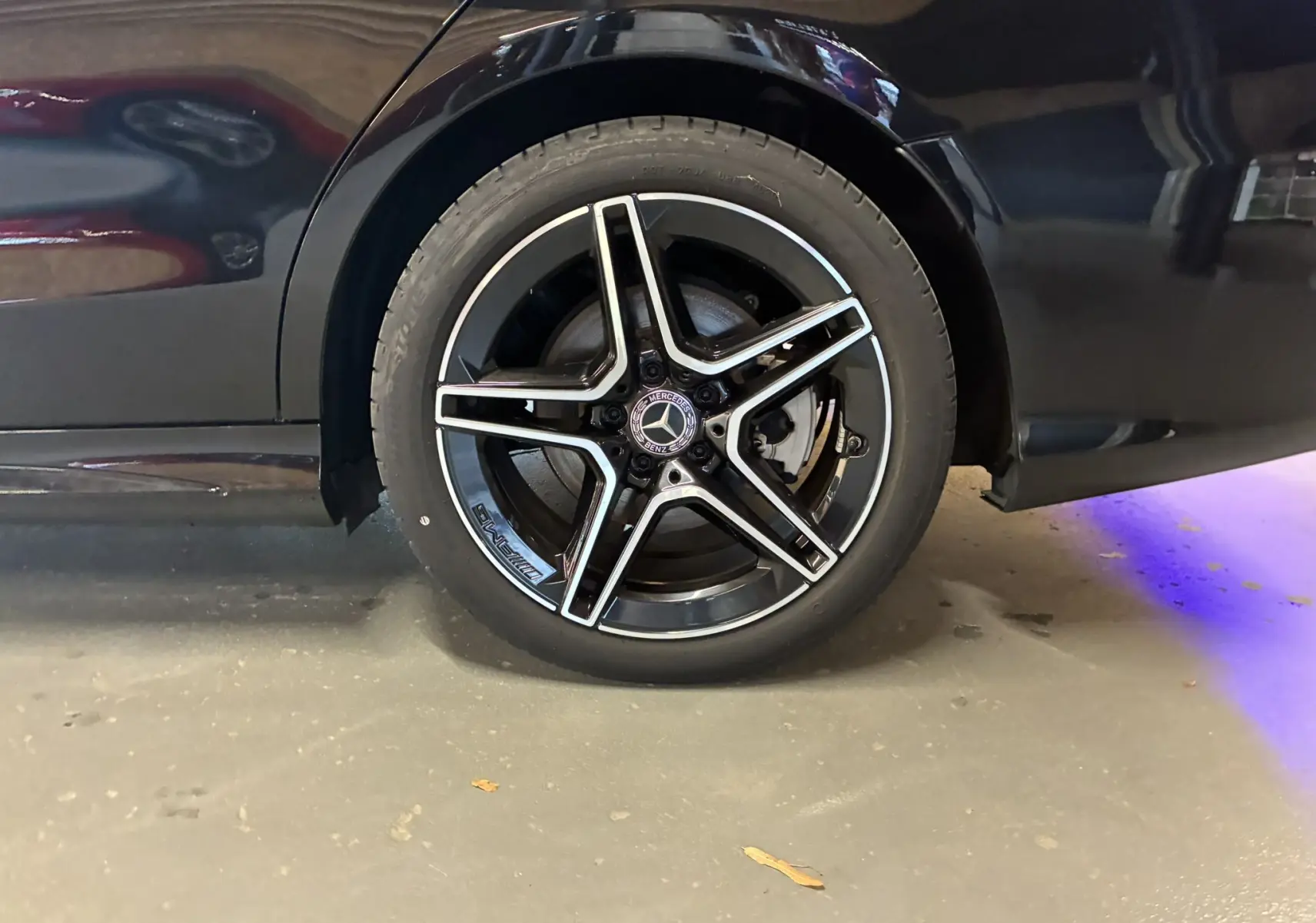 Gros plan sur la roue arrière droite noire métal d'une Mercedes Classe C Break 220D AMG Line avec jante alu 18 bi-ton.