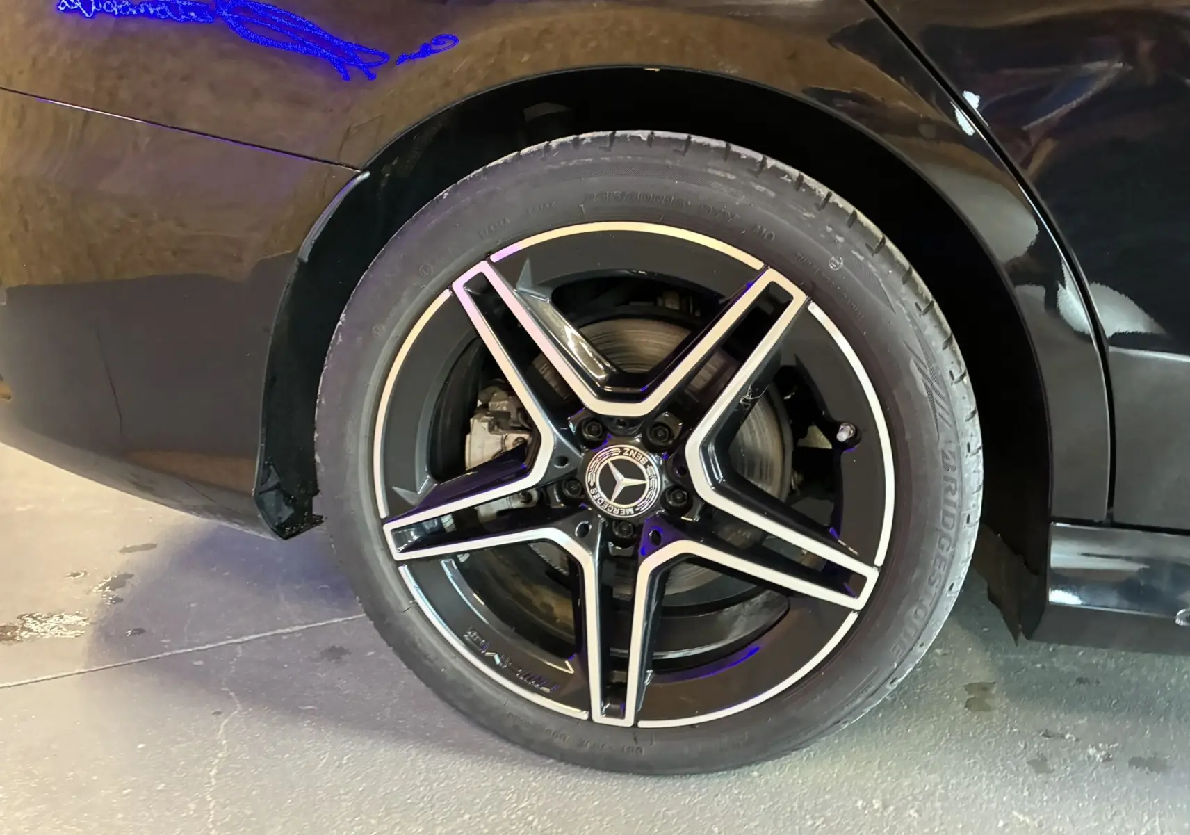 Gros plan sur la roue arrière droite noire métal d'une Mercedes Classe C Break 220D AMG Line avec jante alu 18 bi-ton.