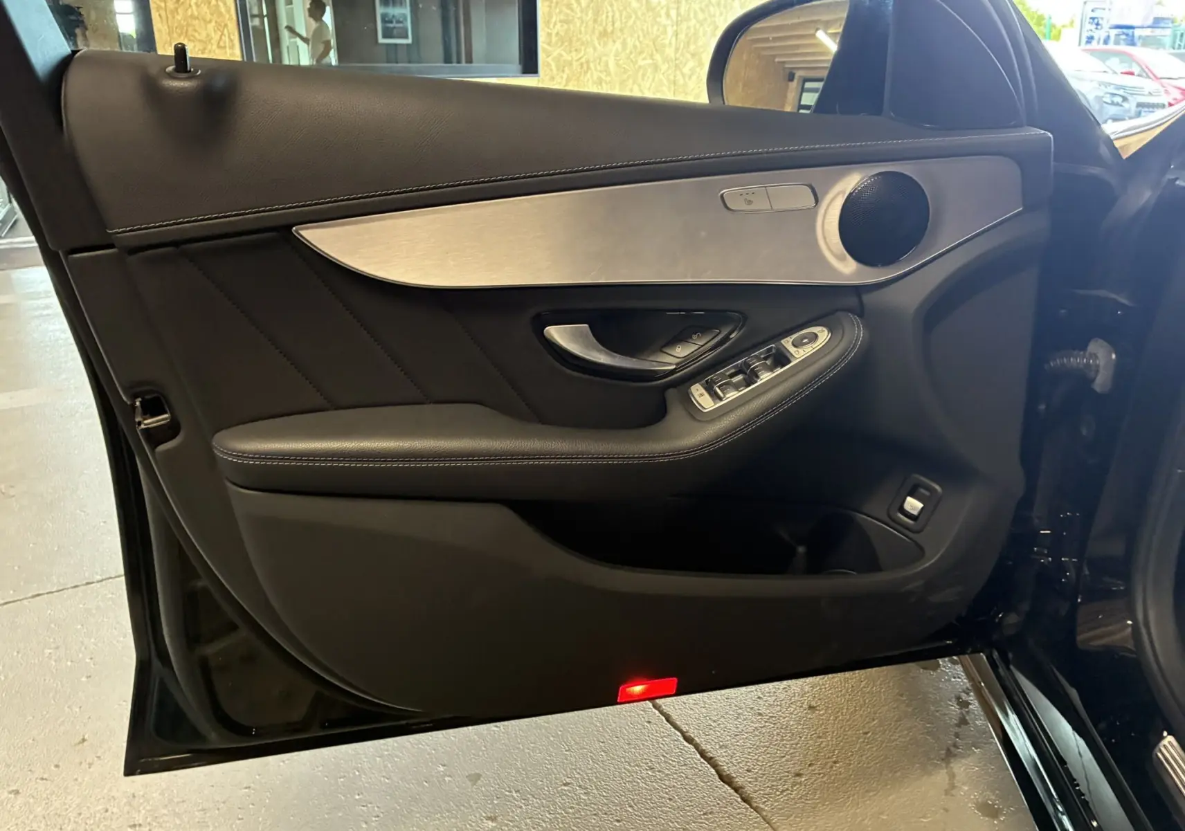 Porte avant gauche ouverte d'une Mercedes Classe C Break noire, avec garniture cuir noir et insert aluminium brossé.