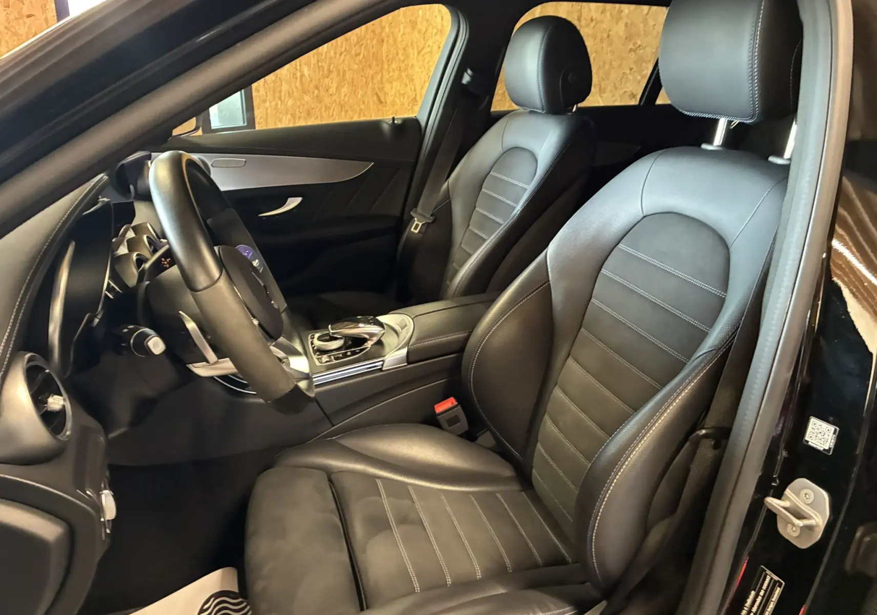 Vue intérieure côté conducteur de la Mercedes Classe C Break 220D AMG Line 2021 avec sièges cuir noir et volant multifonction.