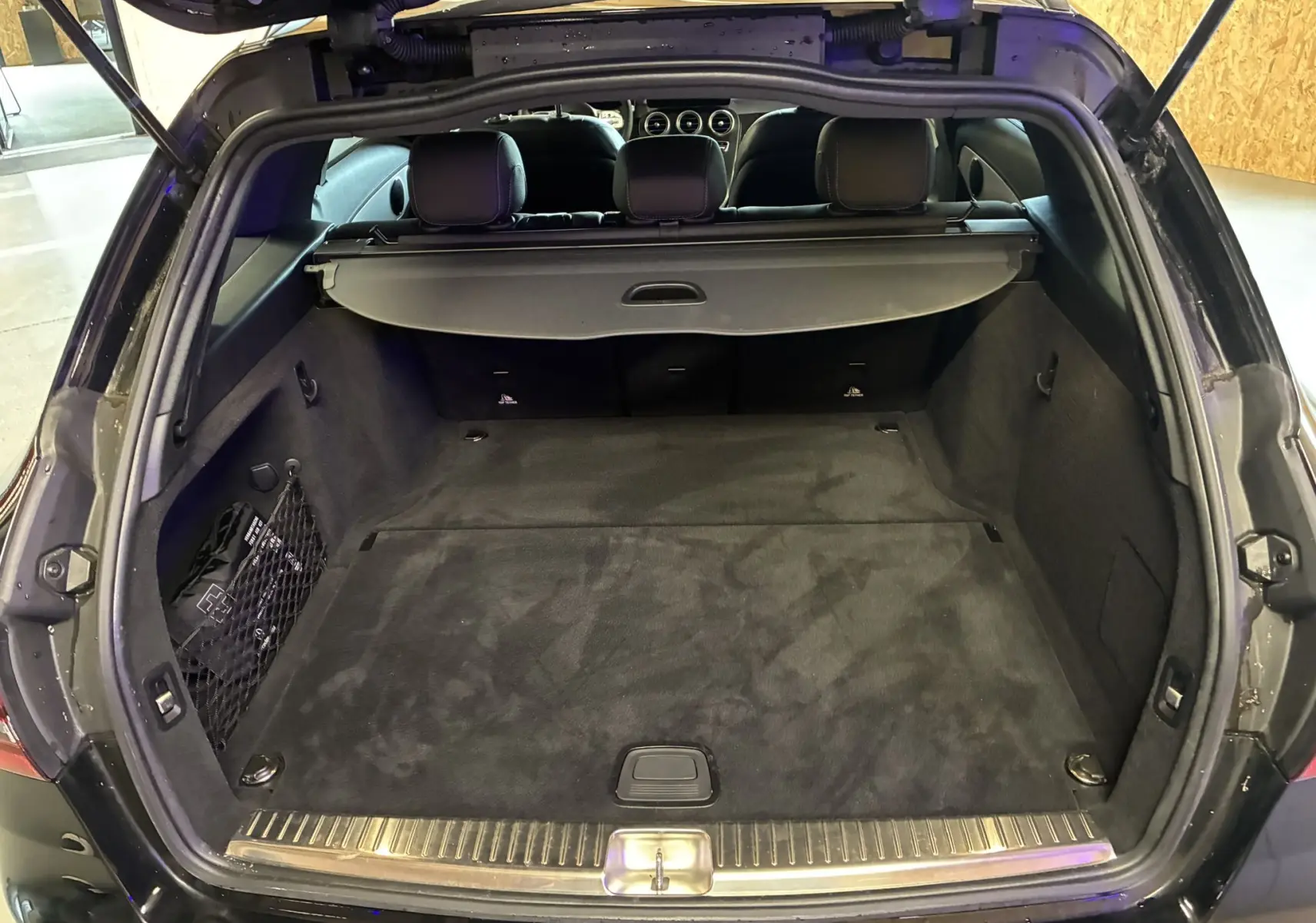 Coffre ouvert d'un Mercedes Classe C Break noir métal, vue arrière montrant l'espace de chargement et la tablette cache-bagages.