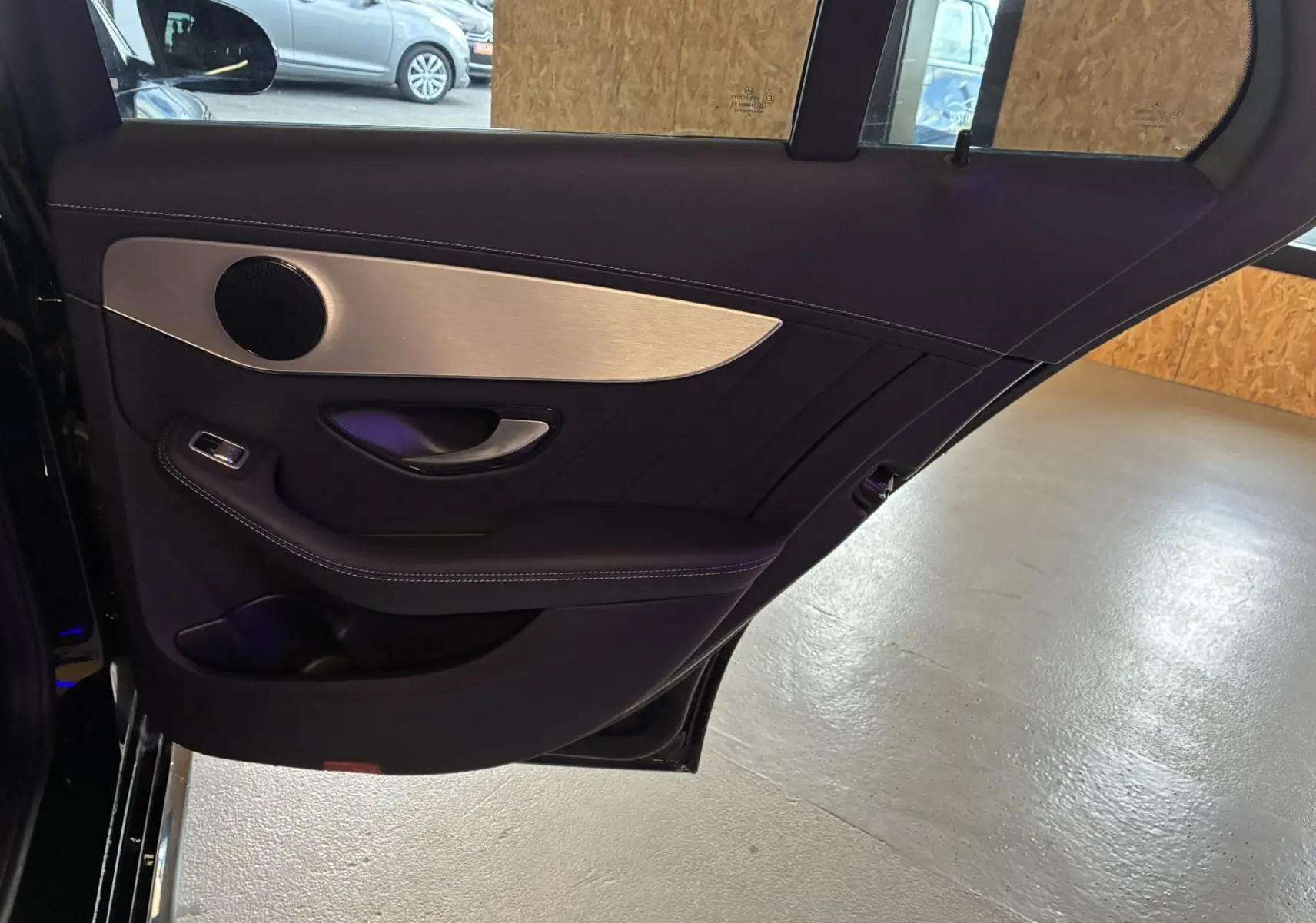 Intérieur de la porte arrière droite d'une Mercedes Classe C Break 220D AMG Line noire, avec habillage cuir et insert aluminium.