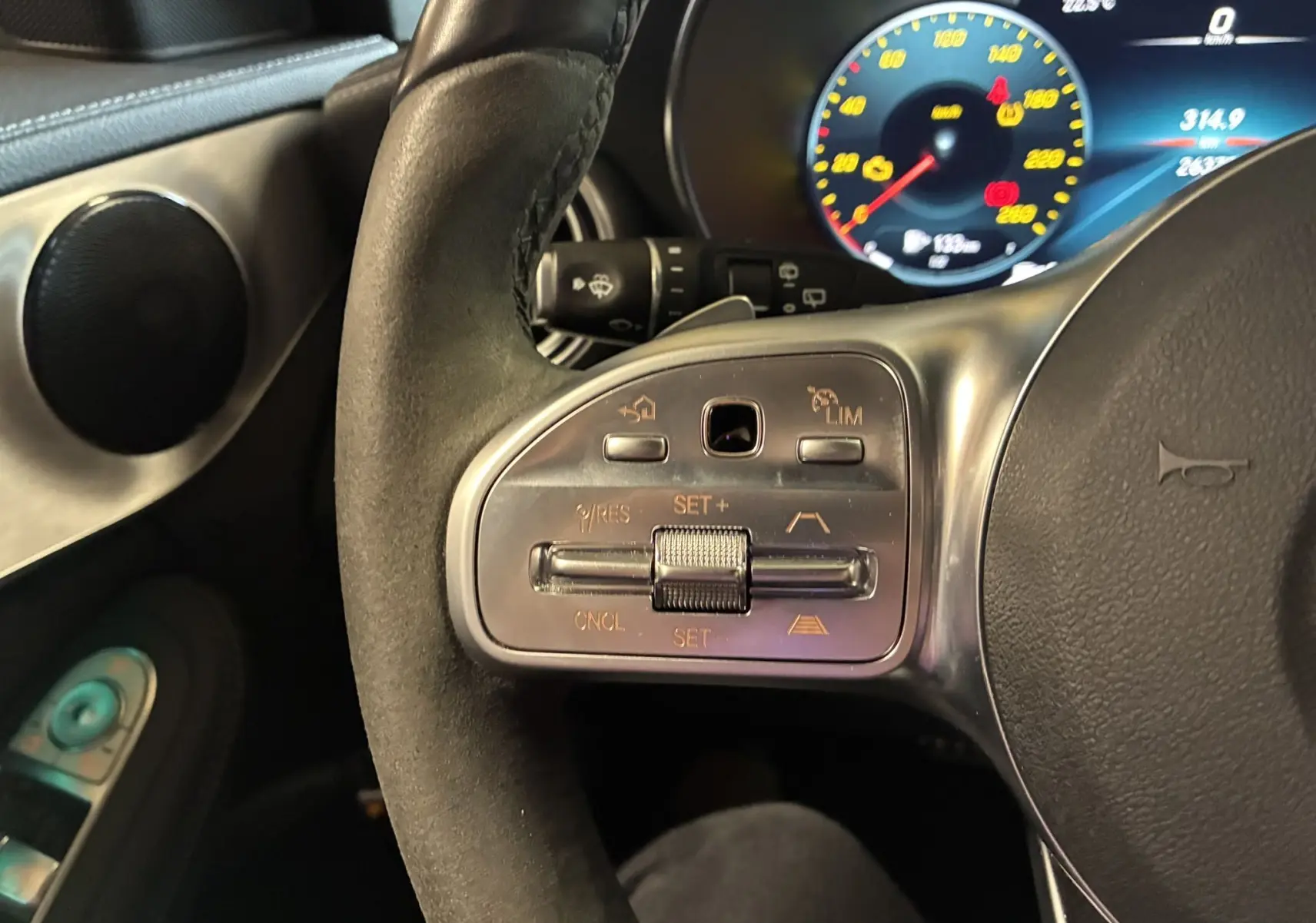 Gros plan sur les commandes à gauche du volant cuir noir du Mercedes Classe C Break 220D AMG Line 2021.