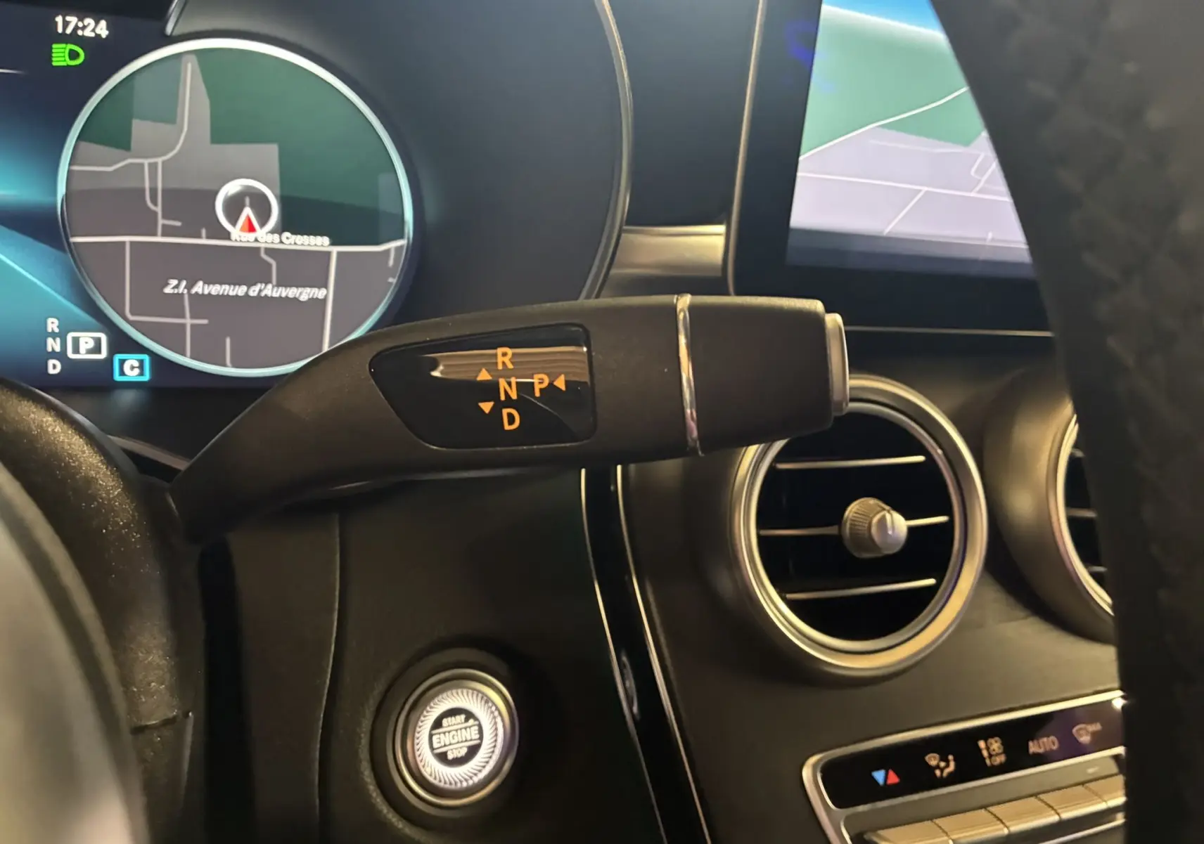 Gros plan sur la commande de boîte automatique et le tableau de bord numérique d'une Mercedes Classe C Break noir métal.