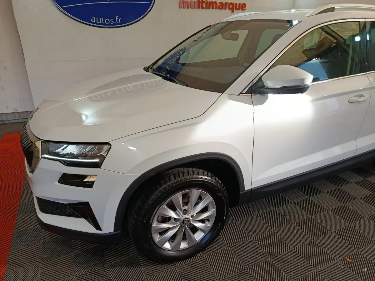 Vue 3/4 avant droit du SUV blanc Skoda Karoq 2024 avec jantes alliage et phares LED ellipsoïdaux.