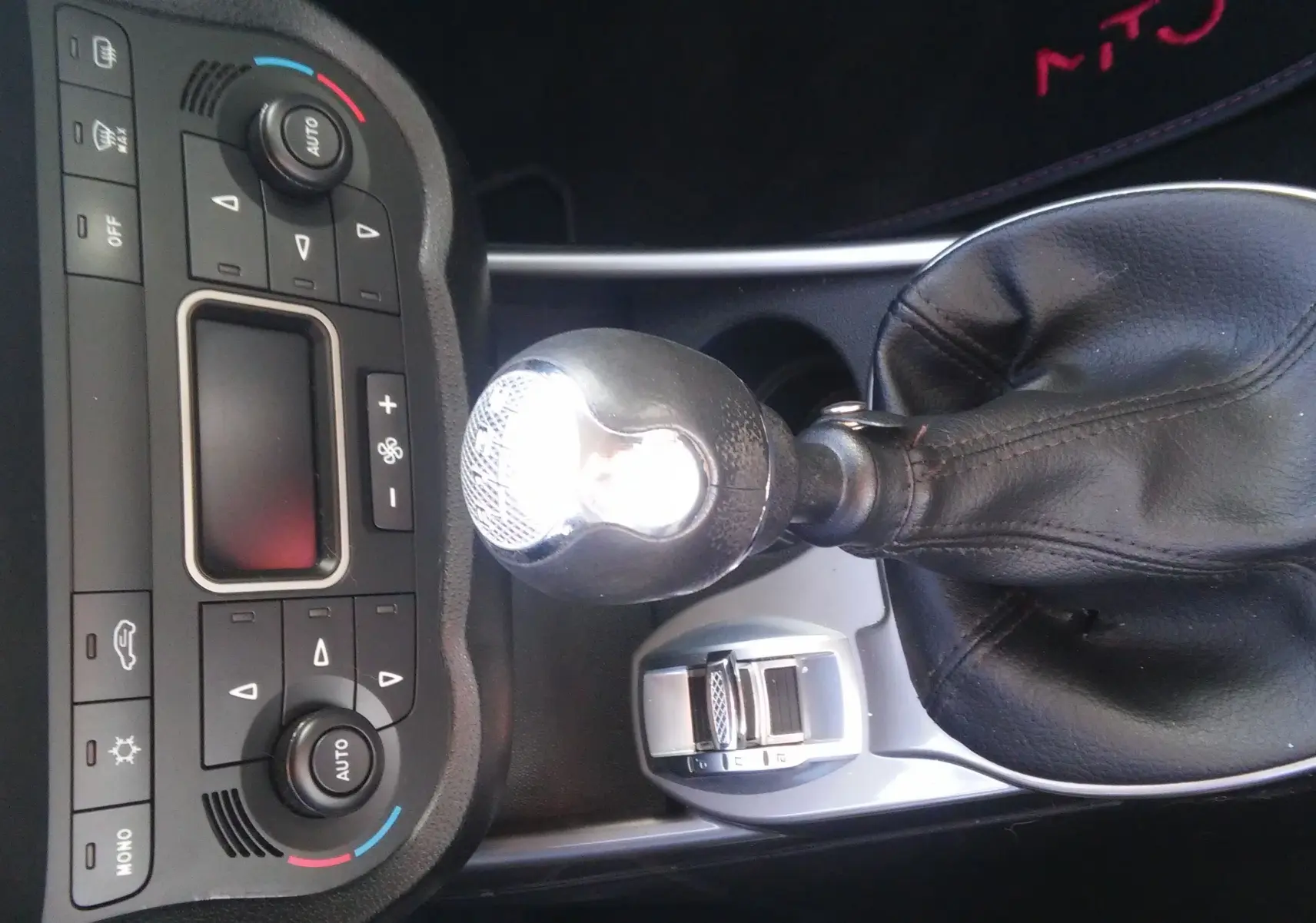 Gros plan sur la console centrale et le levier de vitesse cuir noir d'une Alfa Romeo MiTo rouge de 2010 avec boîte manuelle.