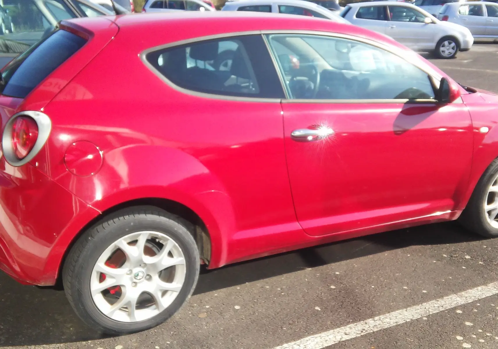 Alfa Romeo MiTo rouge vue de profil côté gauche, soulignant ses jantes alliage et sa silhouette compacte.