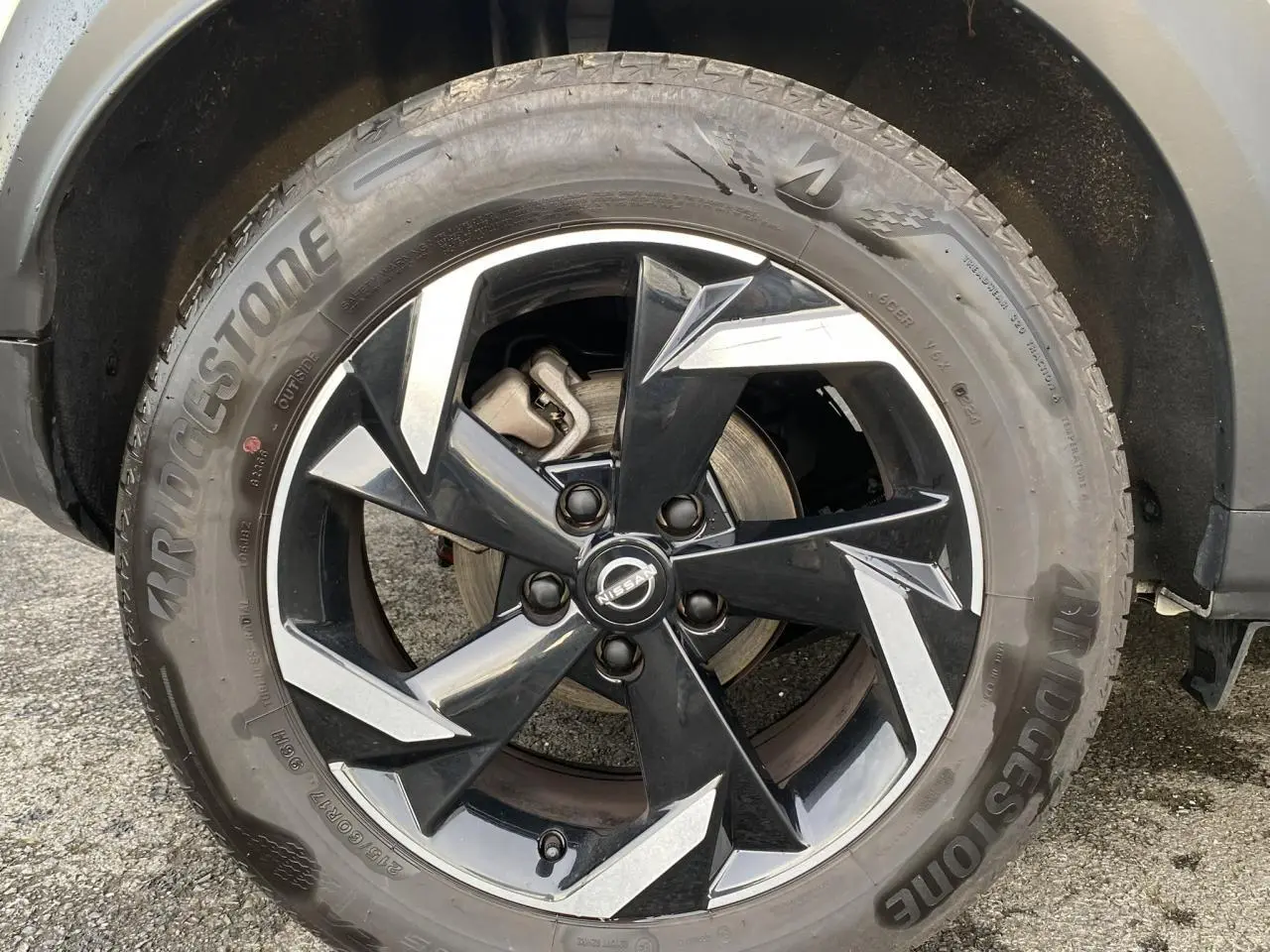 Gros plan sur la jante alliage 17'' noire et argentée du Nissan Juke blanc perle, avec pneu Bridgestone visible.