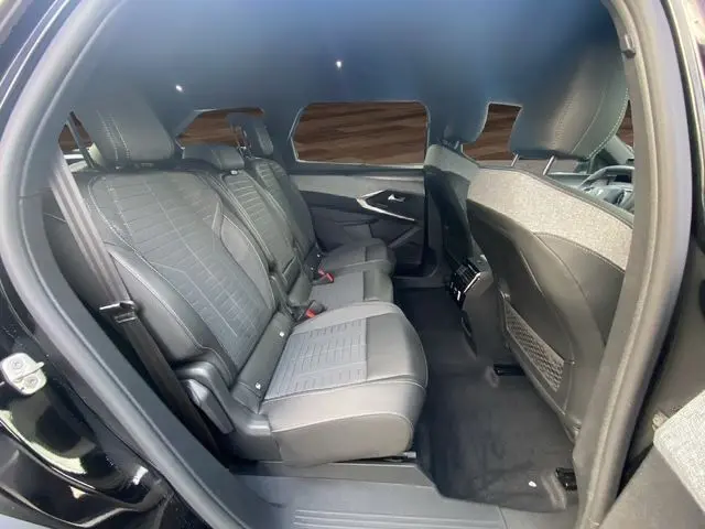 Vue latérale gauche de l'intérieur arrière du Peugeot 5008 noir Perla avec sièges en cuir gris et banquette coulissante.