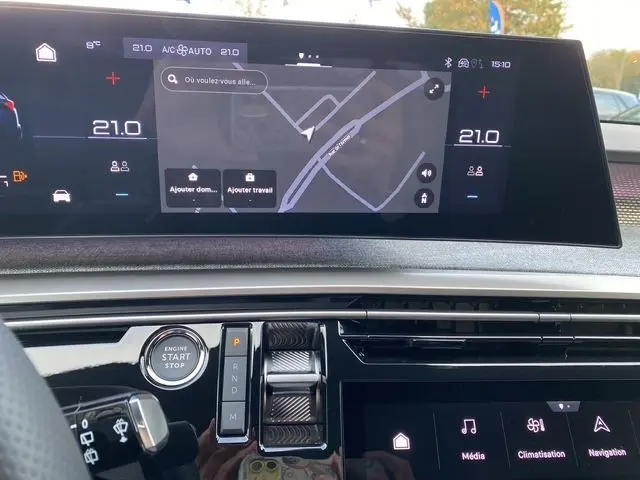 Tableau de bord du Peugeot 5008 2025 avec écran tactile GPS affichant une carte, boutons de commande et démarrage moteur.