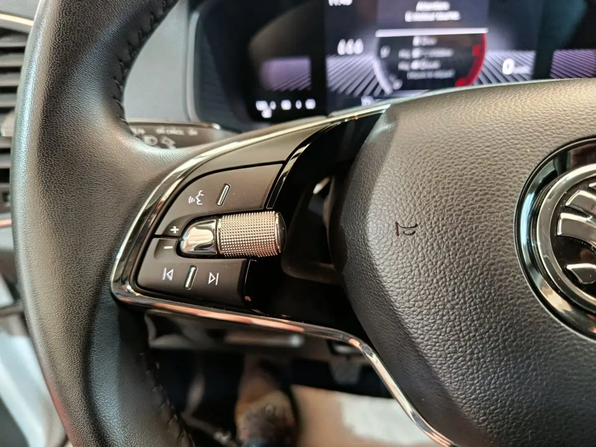 Gros plan sur le volant cuir noir du Skoda Karoq 2024, avec commandes multifonctions et molette métallique côté gauche.