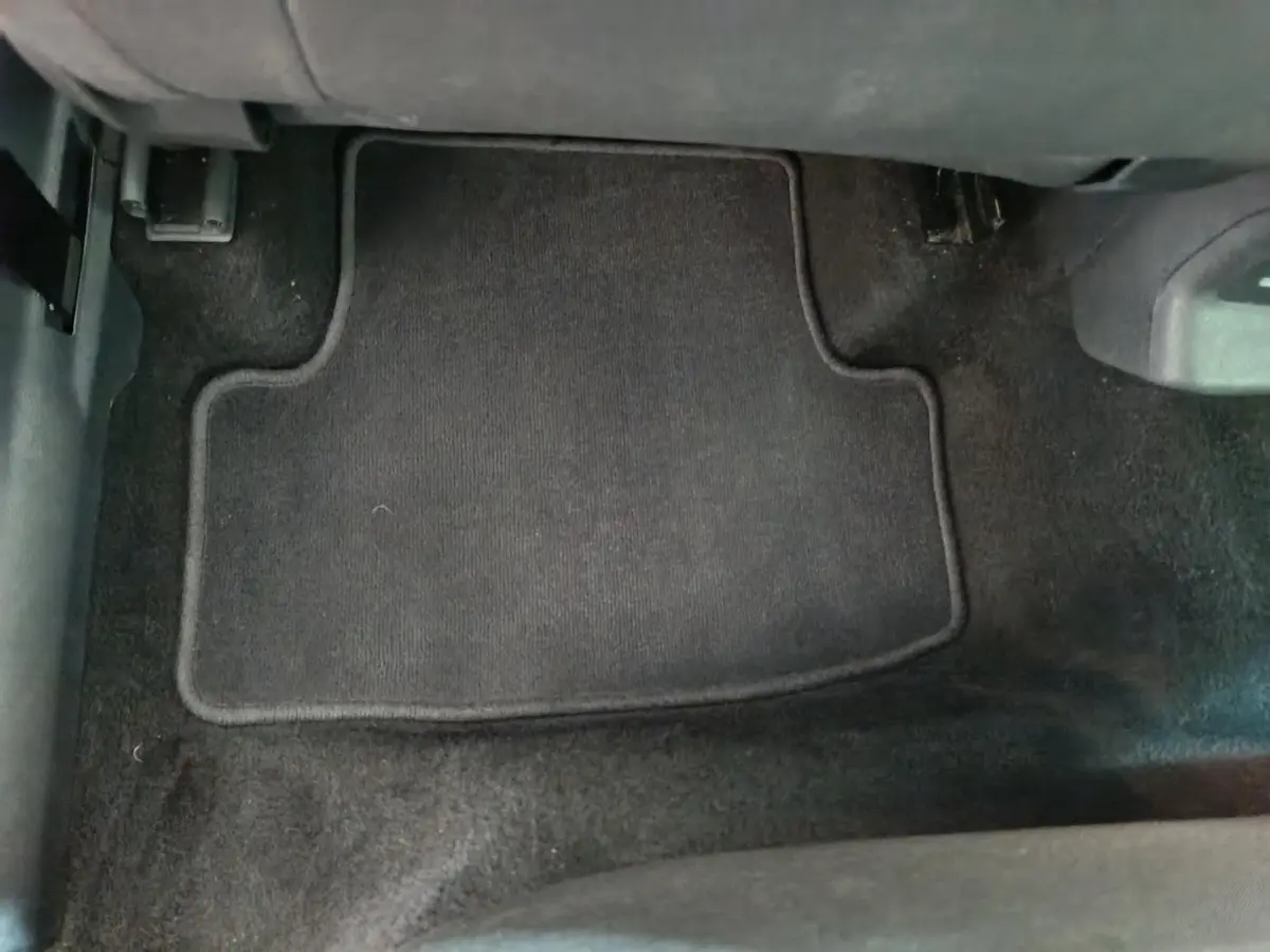 Vue rapprochée du tapis de sol noir côté conducteur dans l’habitacle du Skoda Karoq 2024 blanc.