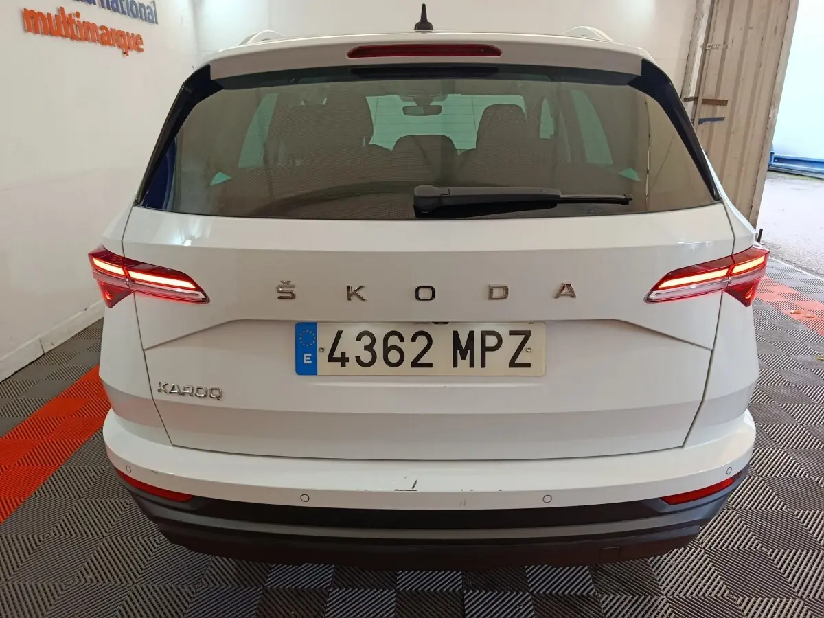 Vue arrière d'un Skoda Karoq blanc 2024 avec feux LED allumés et plaque d'immatriculation visible.