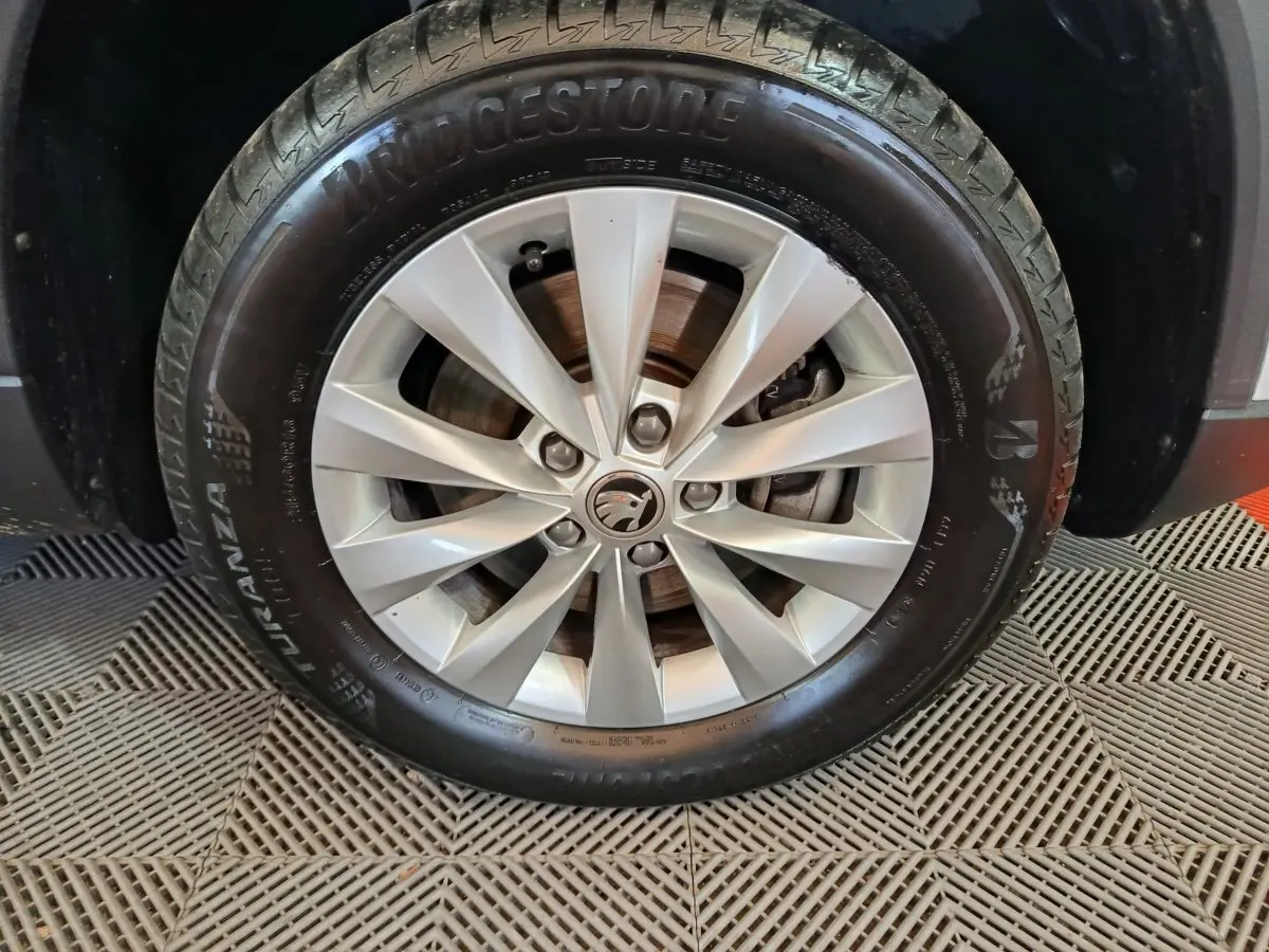 Gros plan sur la roue avant droite d'un Skoda Karoq blanc 2024 avec jante alliage et pneu Bridgestone.