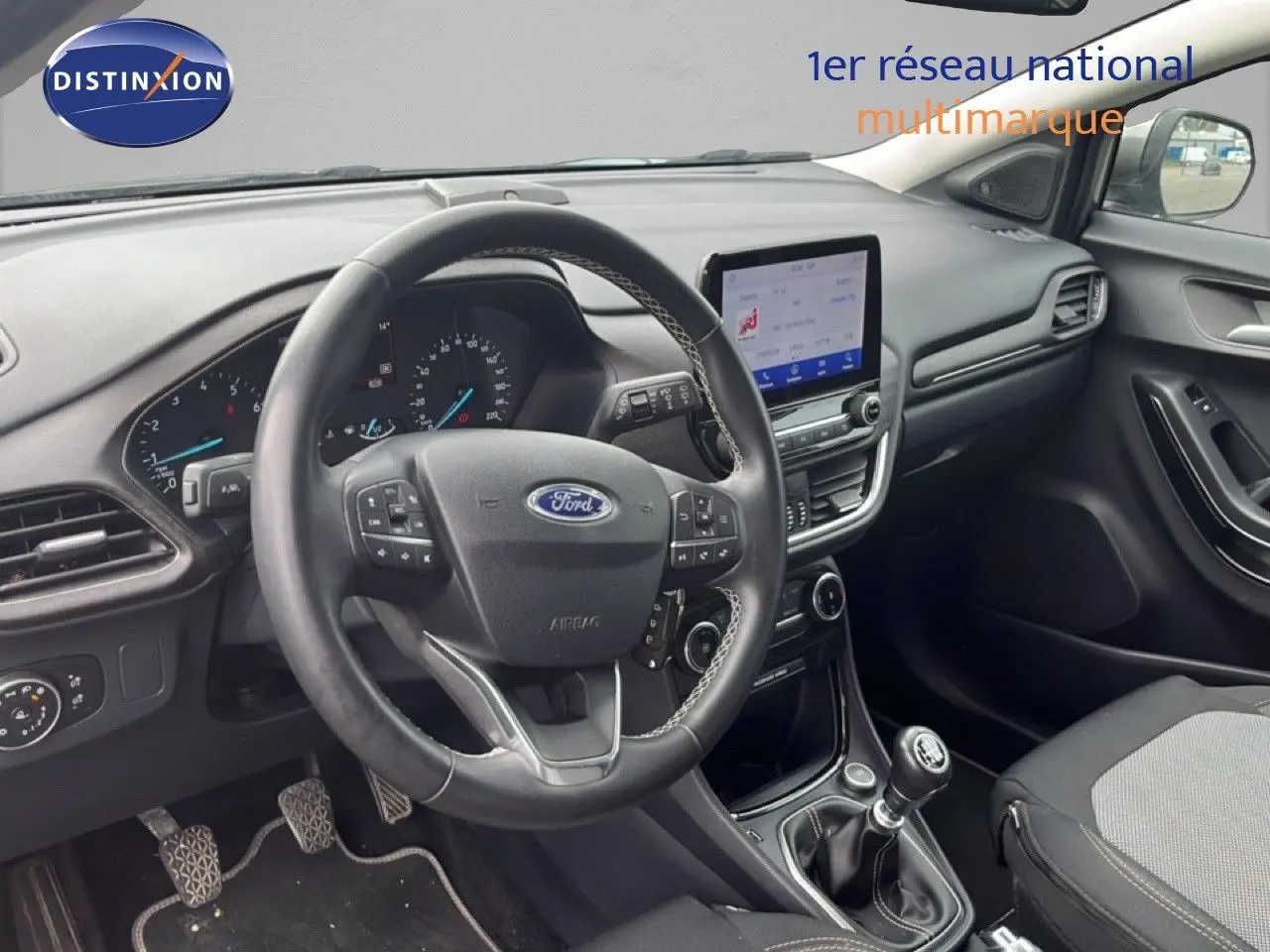 Vue intérieure du poste de conduite du Ford Puma gris 2021, avec volant multifonction et écran tactile central.