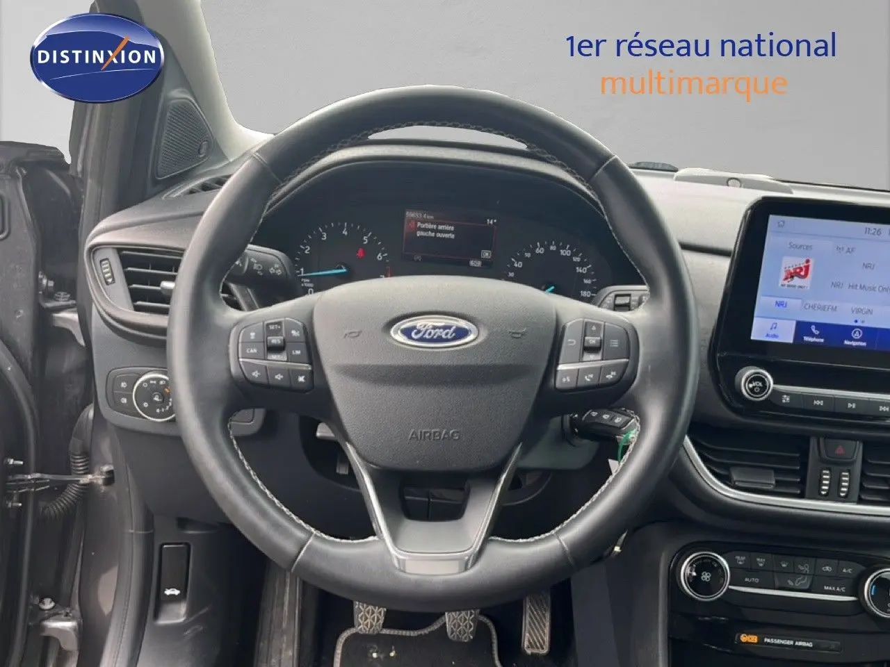 Vue intérieure centrée sur le volant Ford Puma gris 2021 avec tableau de bord numérique et écran tactile central.