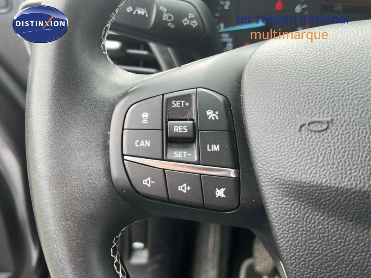 Gros plan sur les commandes du volant noir du Ford Puma gris, version 1.0 EcoBoost 125 mHev Titanium de 2021.