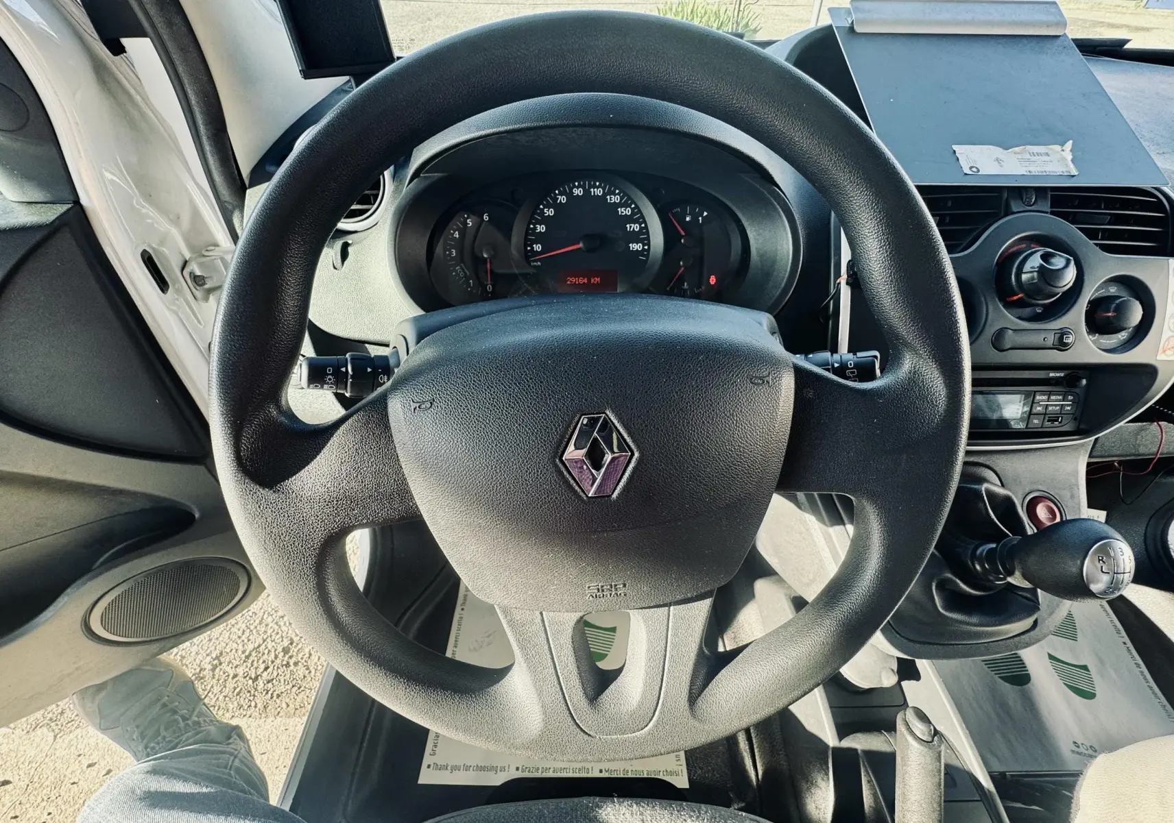 Vue intérieure centrée sur le volant noir Renault avec tableau de bord et levier de vitesse manuel visibles.