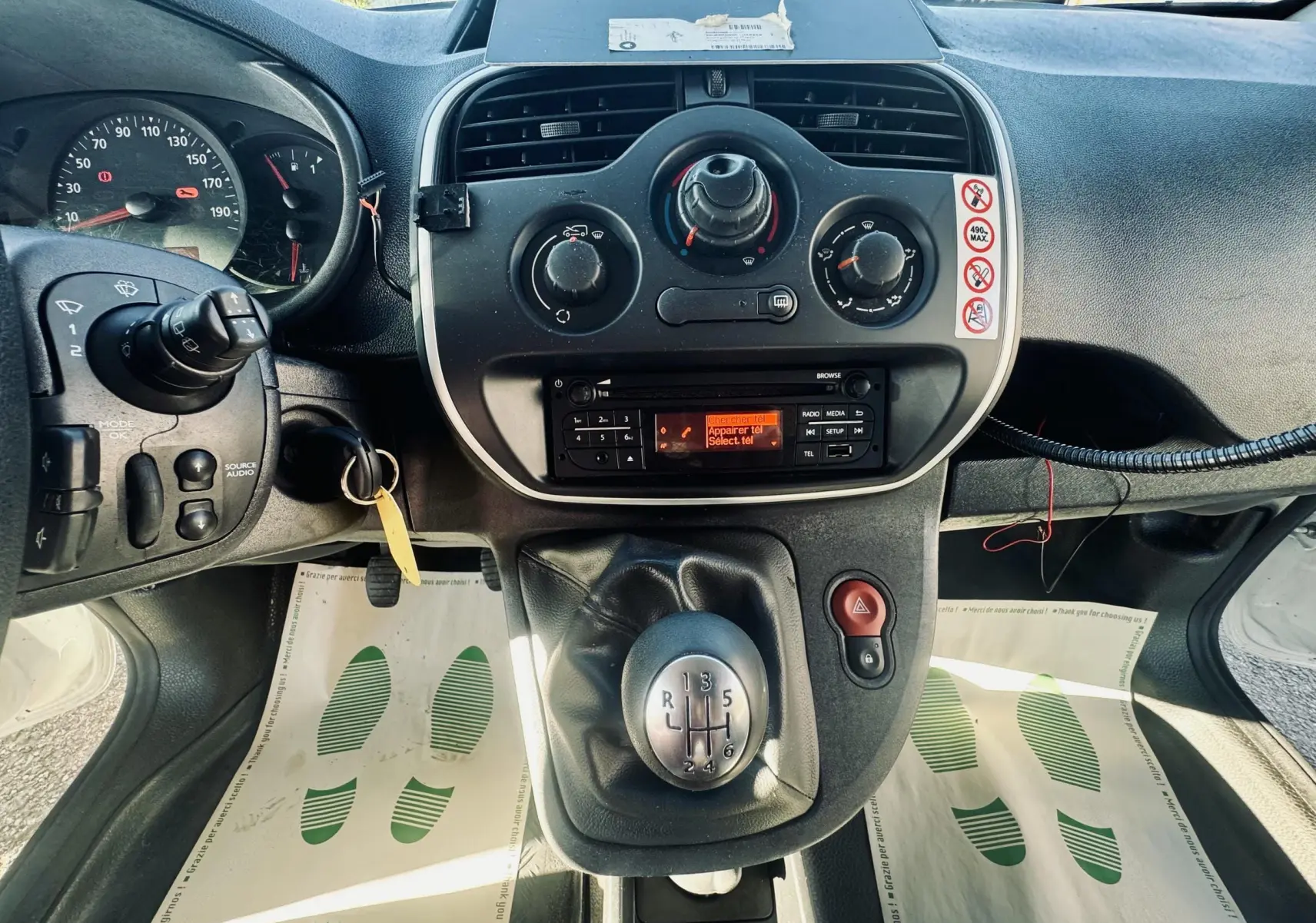Vue intérieure centrée sur la console centrale et levier de vitesse manuel du Renault Kangoo blanc de 2021.