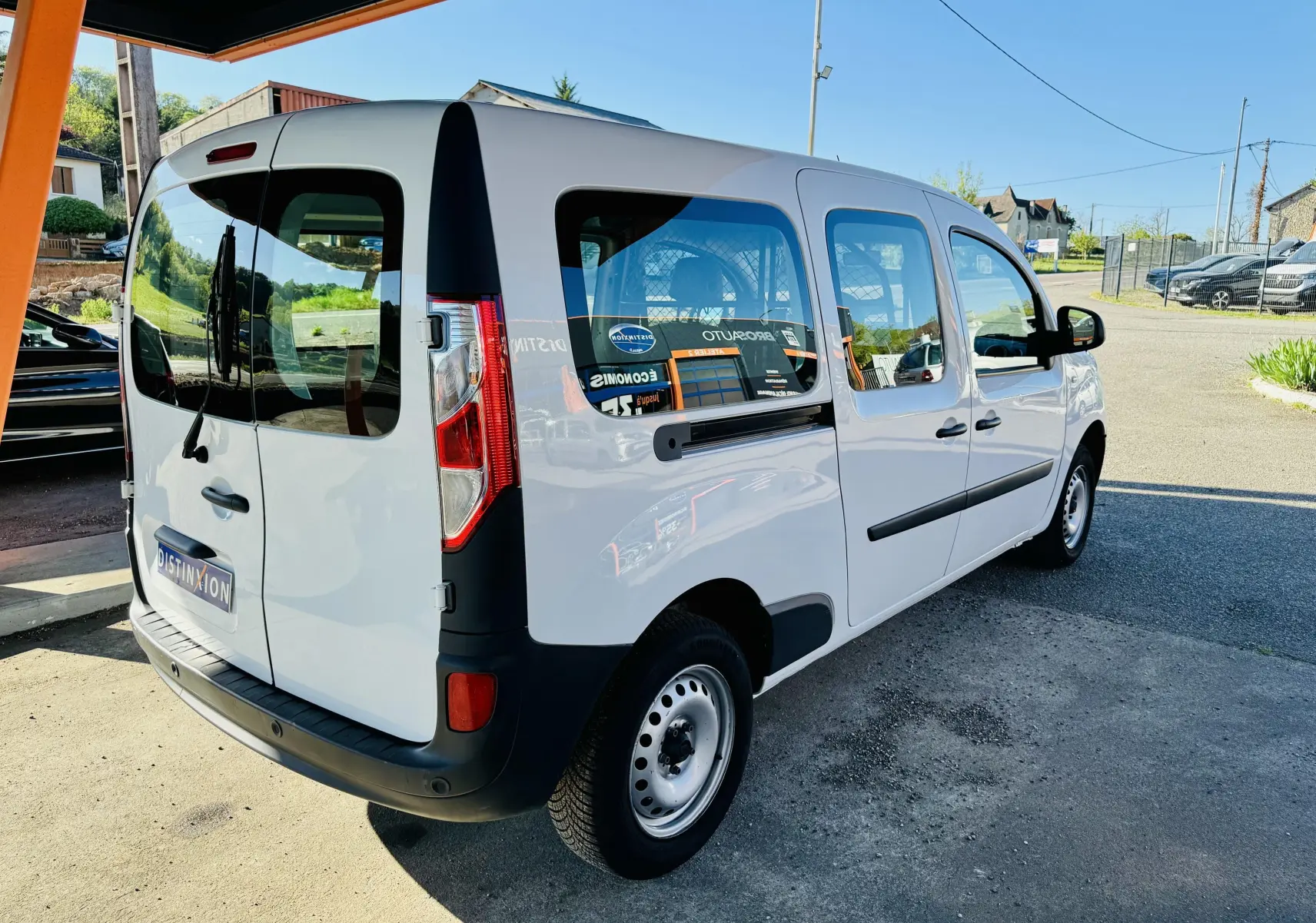 Renault Kangoo Maxi blanc vu en 3/4 arrière droit, avec vitres teintées et protections noires sur les portes.
