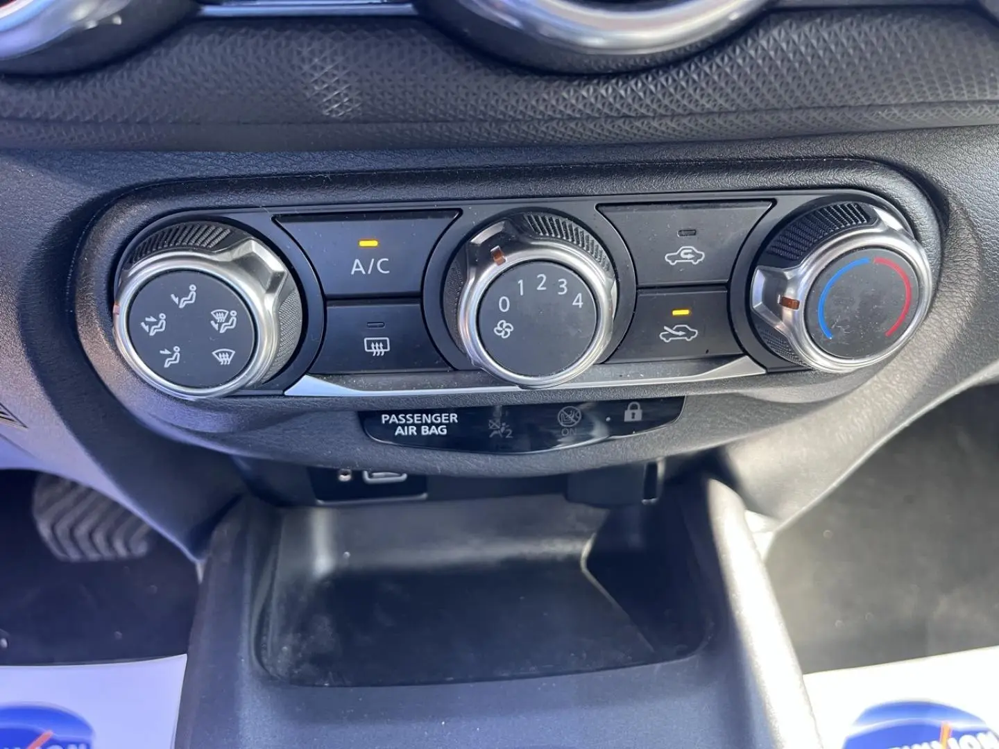 Gros plan sur les commandes de climatisation manuelle du Nissan Juke gris, avec réglages de ventilation et température.