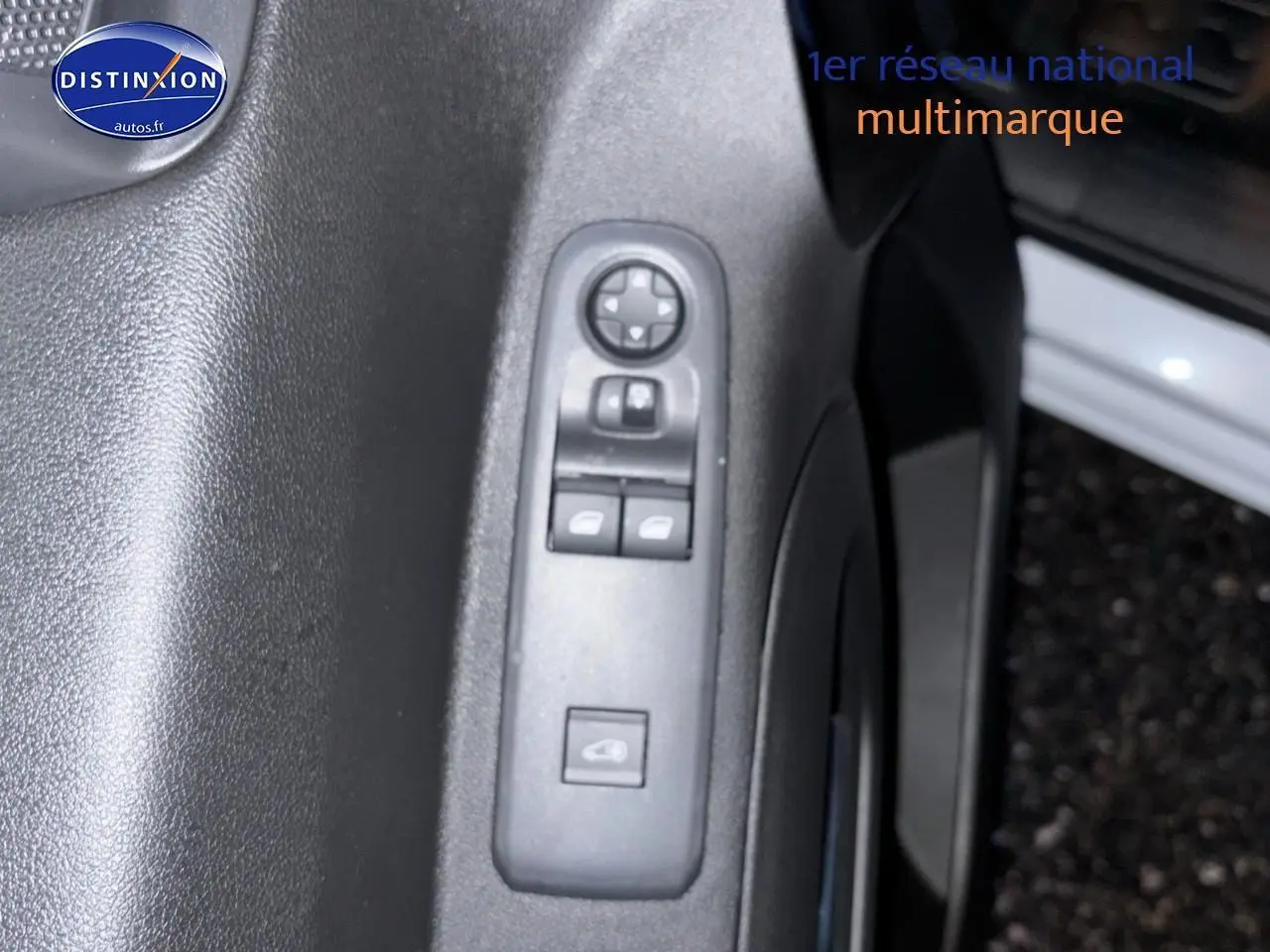 Gros plan sur les commandes électriques des vitres et rétroviseurs côté gauche d’un Citroën Berlingo Fourgon blanc.