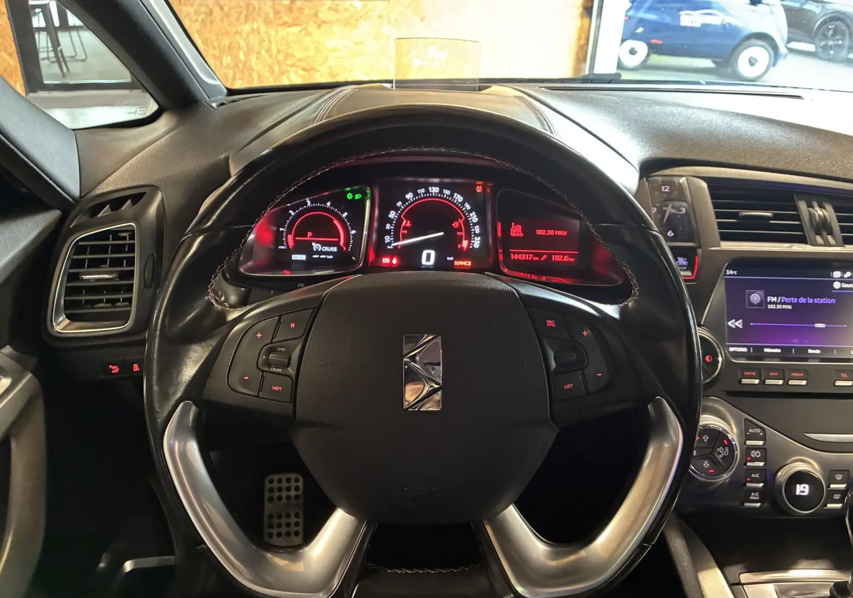 Vue intérieure centrée sur le volant noir et le tableau de bord numérique rouge de la DS5 gris 2018.