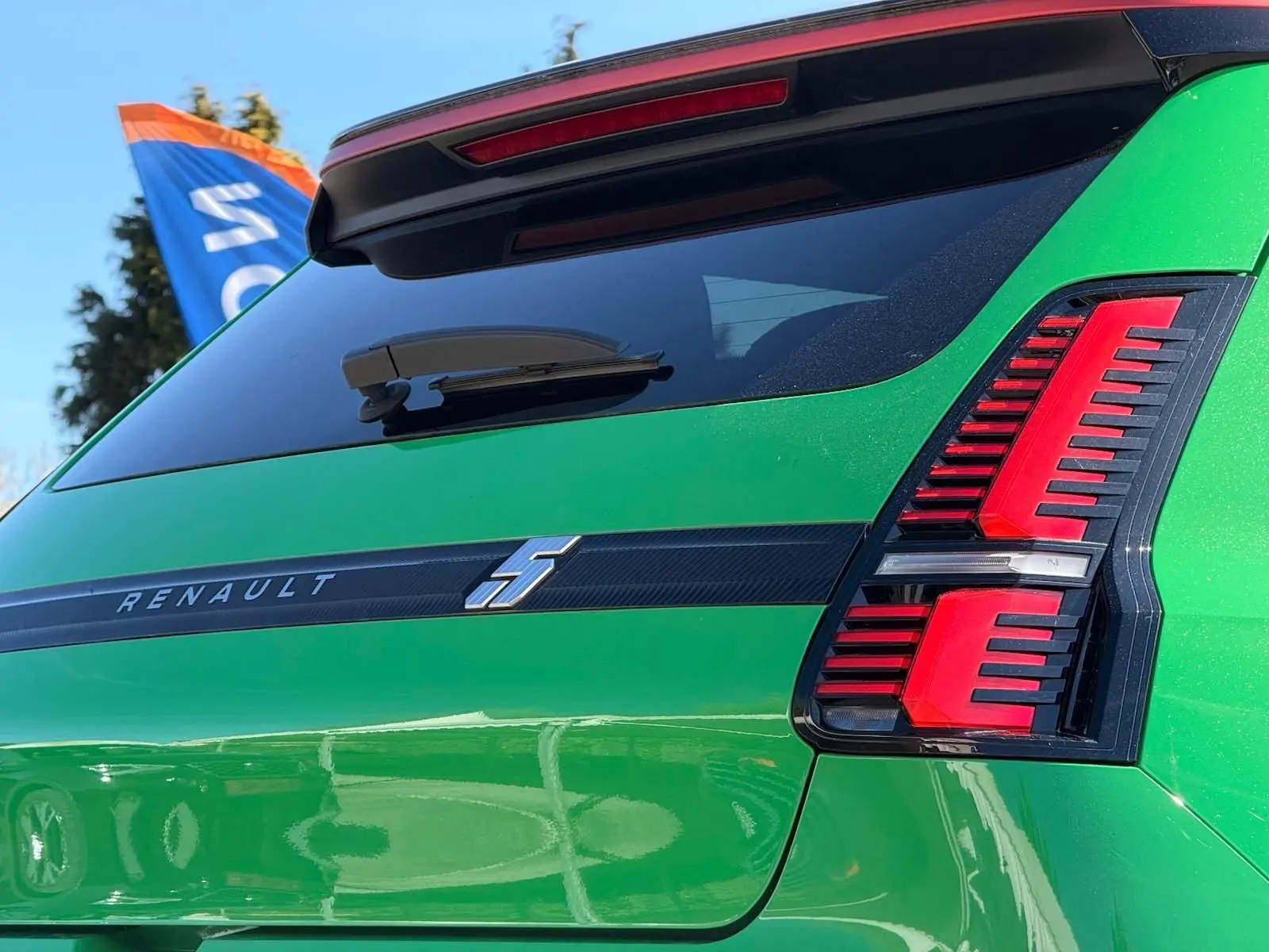 Vue arrière droite d'une Renault R5 E-TECH électrique en vert Pop avec feux arrière rouges et bande noire siglée Renault.