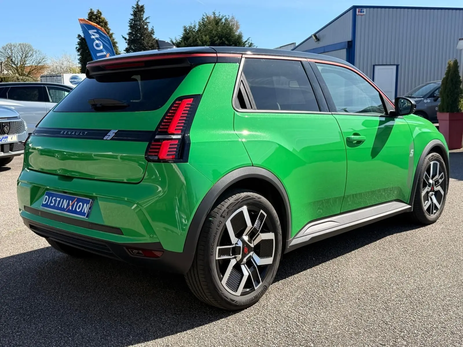 Vue 3/4 arrière droite d'une Renault R5 E-TECH électrique 2024 vert Pop avec toit noir étoile et jantes bi-ton.