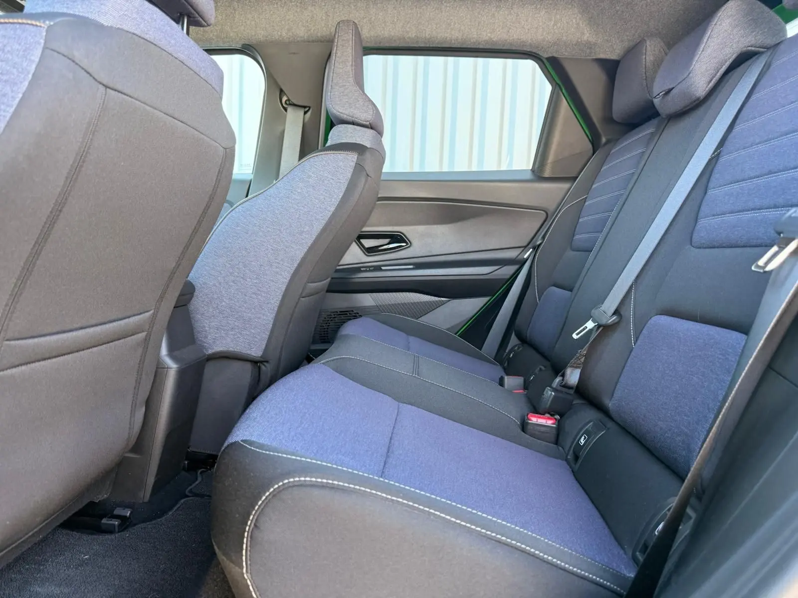 Vue latérale intérieure arrière de la Renault R5 E-TECH 2024, sièges en textile bleu et gris avec surpiqûres contrastantes.