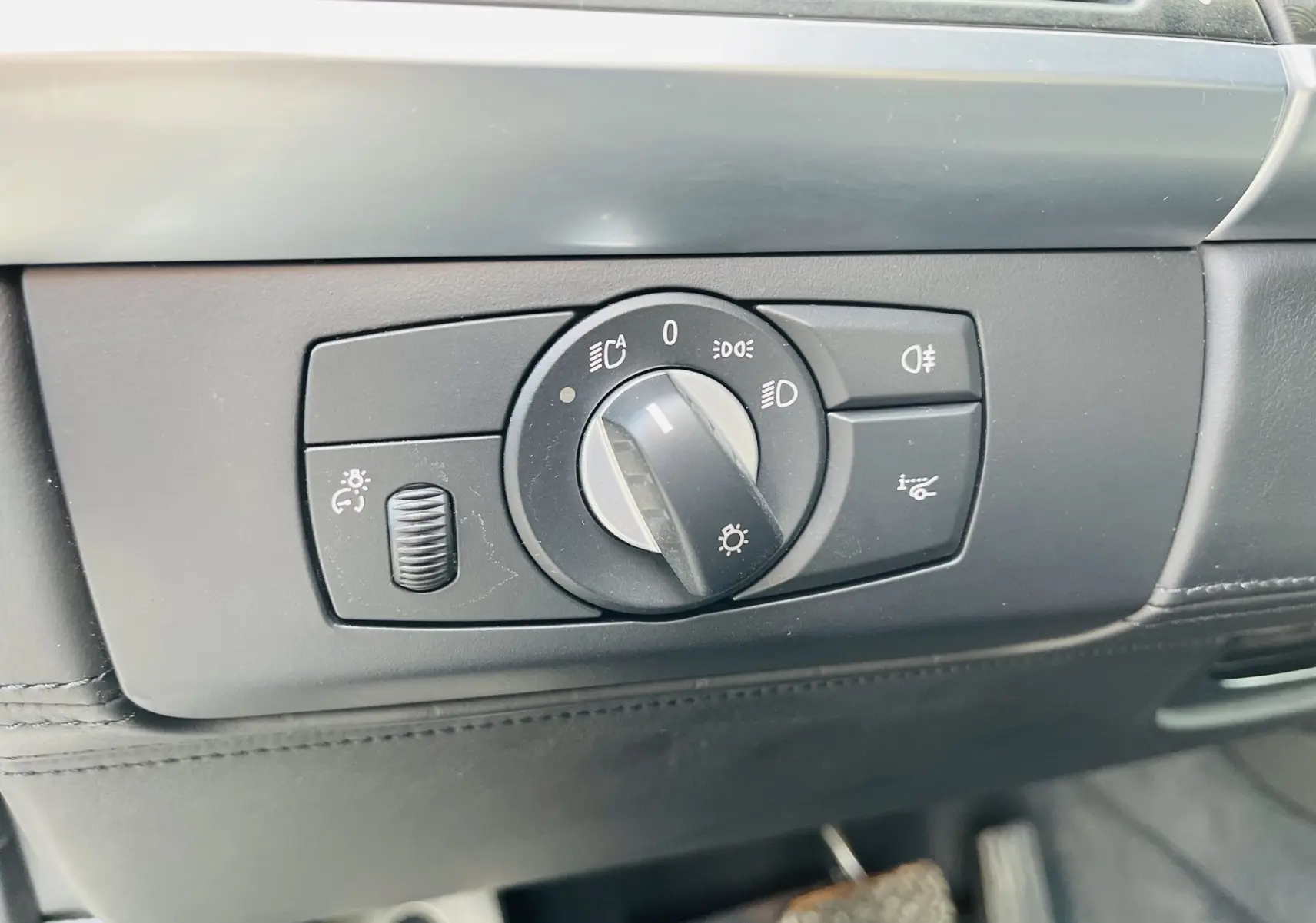 Gros plan sur le bouton de commande des phares dans l'habitacle noir du BMW X6 blanc 2013.