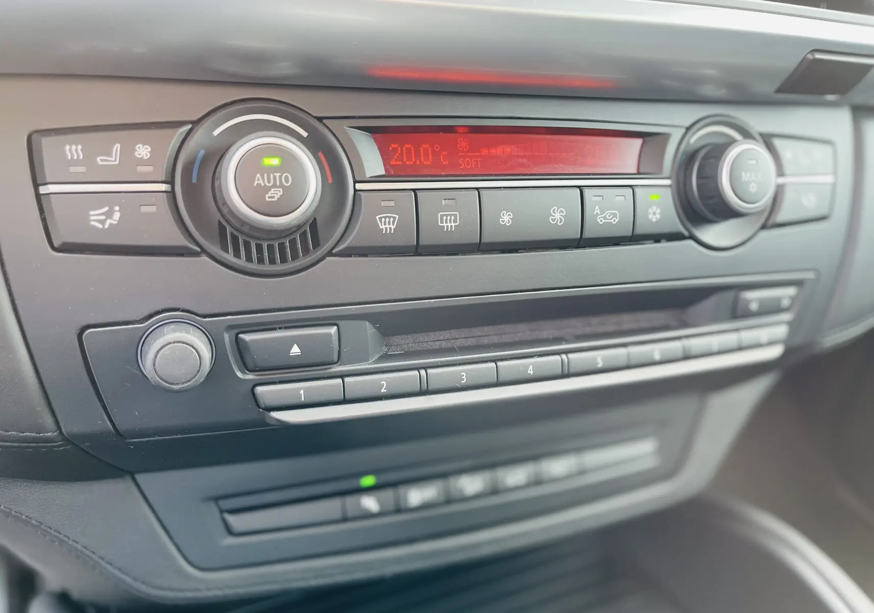 Gros plan sur la console centrale noire du BMW X6 50D, affichant les commandes de climatisation et audio.