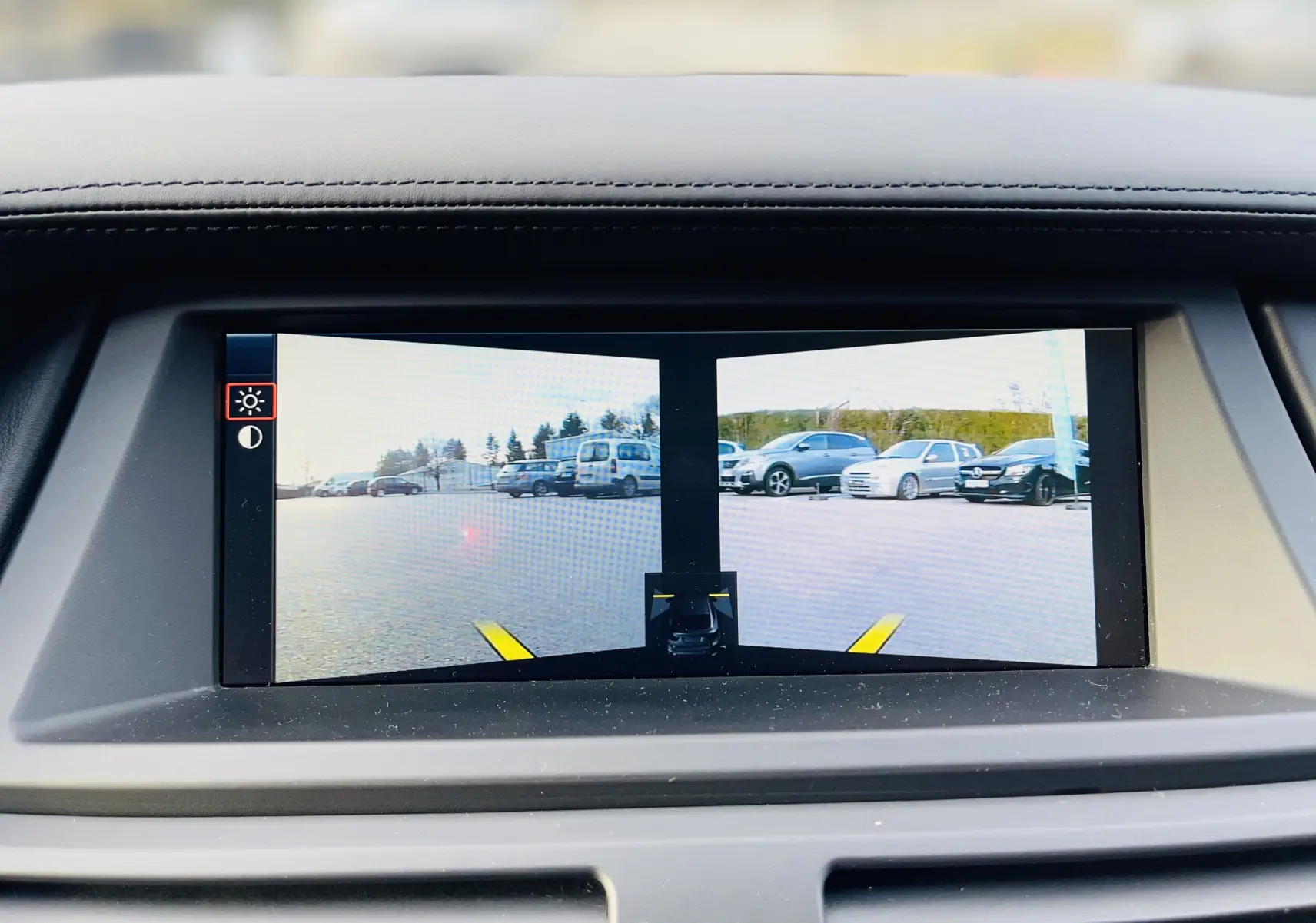 Affichage de la caméra de recul avec vue Top View sur l'écran intérieur du BMW X6 blanc, montrant l'arrière et le parking.