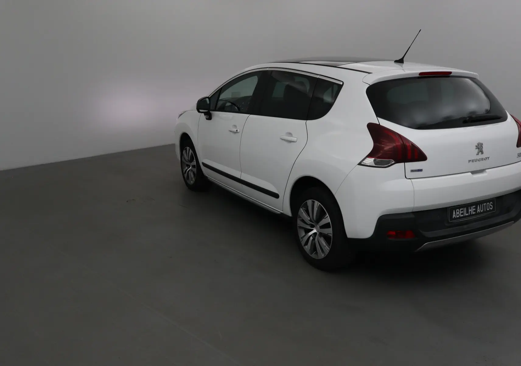 Vue 3/4 arrière droite d'un Peugeot 3008 blanc de 2015 avec jantes alliage et vitres teintées.