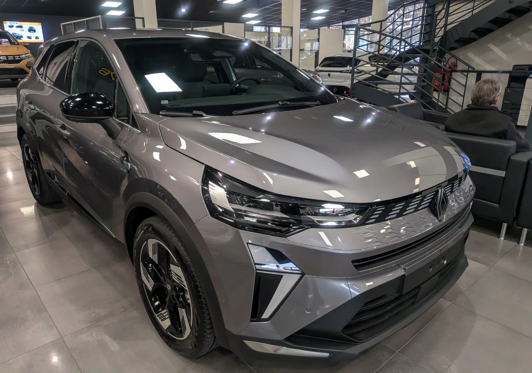 Renault SYMBIOZ E-Tech gris Cassiopé en 3/4 avant droit, avec calandre moderne et jantes biton distinctives.