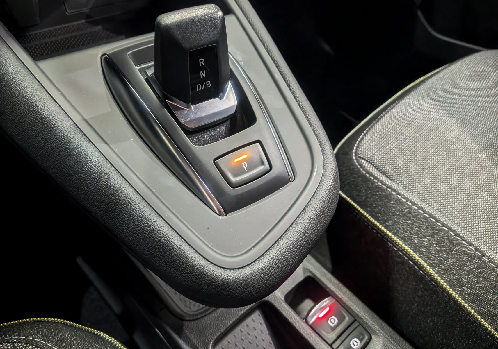 Gros plan sur la console centrale du Renault Symbioz gris Cassiopé, montrant le levier de vitesses automatique et les commandes de frein à main électrique.