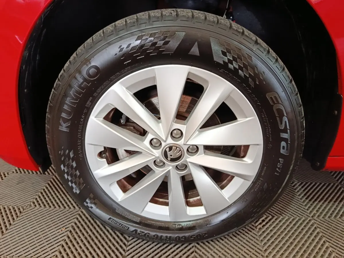 Gros plan sur la roue avant droite d’une Skoda Kamiq rouge avec jante argentée et pneu Kumho Ecsta.