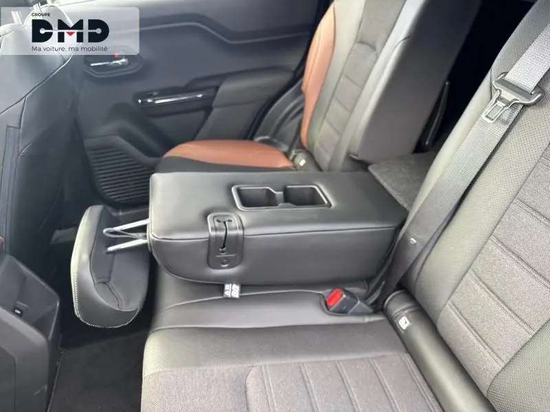 Vue intérieure côté droit de la banquette arrière du Suzuki Vitara 2026 avec accoudoir central noir et sièges bi-matière marron et noir.