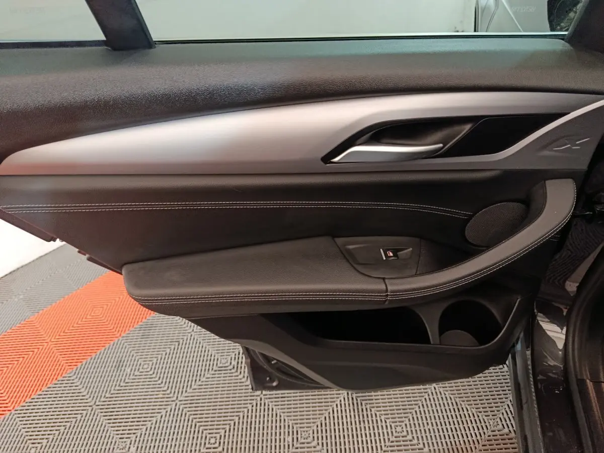 Vue intérieure côté gauche de la porte BMW X3 xDrive30e 2020, garniture noire avec insert argenté et surpiqûres blanches.