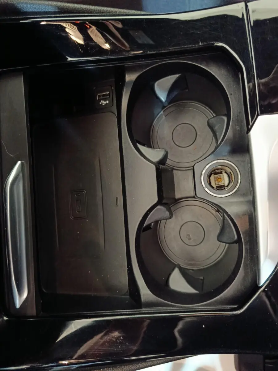 Gros plan sur la console centrale noire du BMW X3 xDrive30e 2020, avec porte-gobelets et prise USB visible.