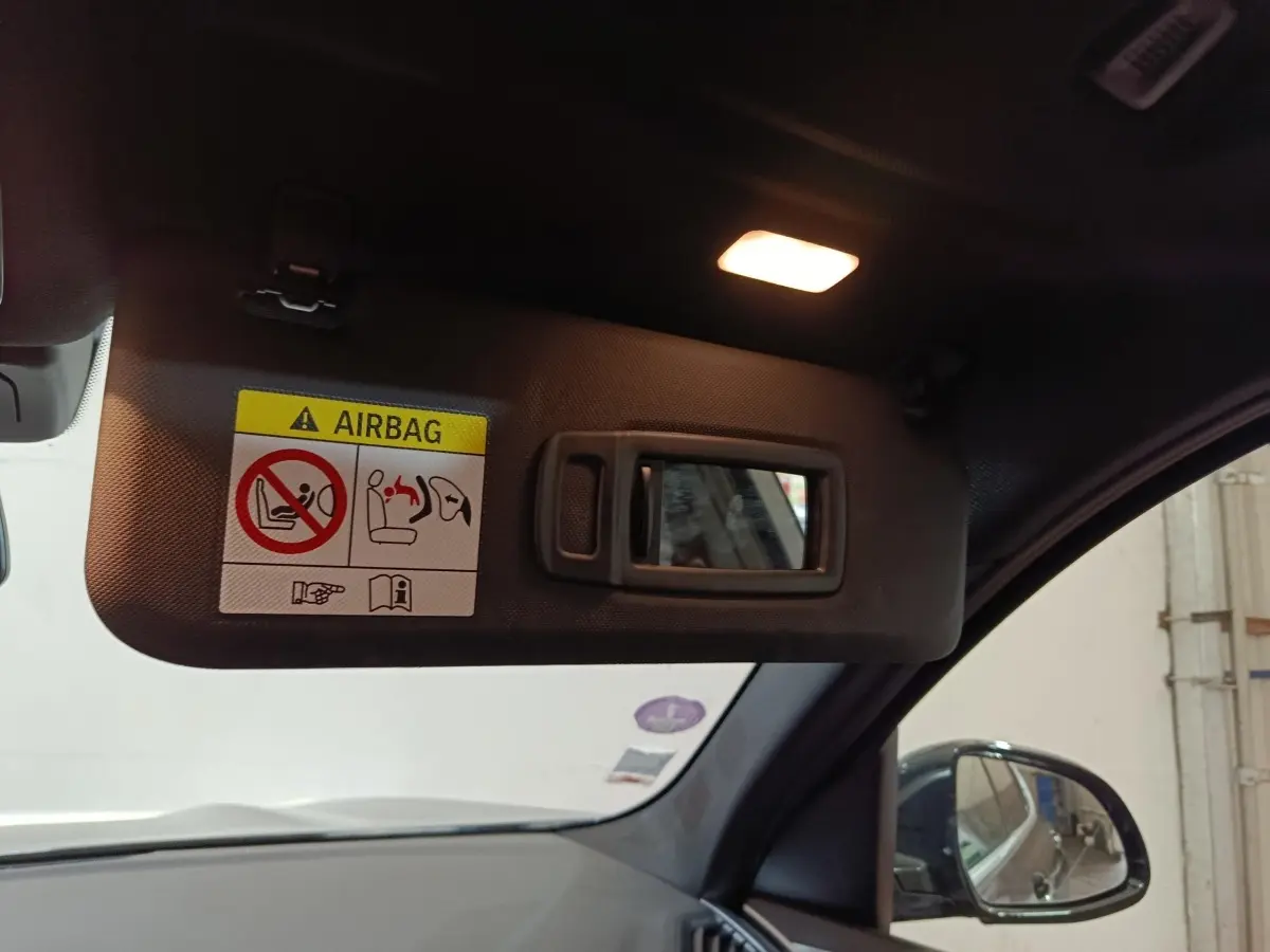 Détail du pare-soleil côté conducteur avec miroir intégré et avertissement airbag, intérieur noir du BMW X3 gris foncé.
