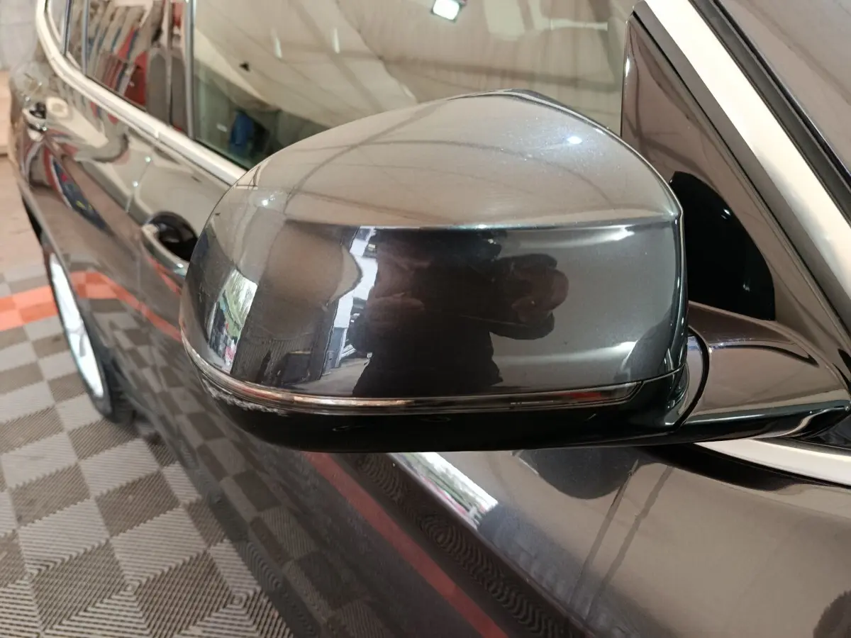 Gros plan sur le rétroviseur côté gauche gris foncé du BMW X3 xDrive30e 2020 avec carrosserie brillante et jante visible.