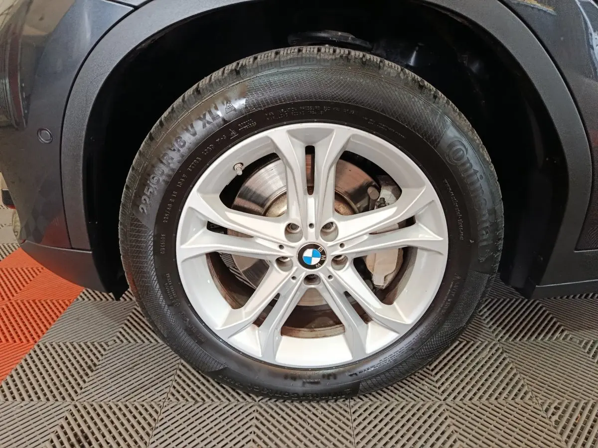 Gros plan sur la roue avant droite gris foncé du BMW X3 xDrive30e avec jante alliage à 5 doubles branches.