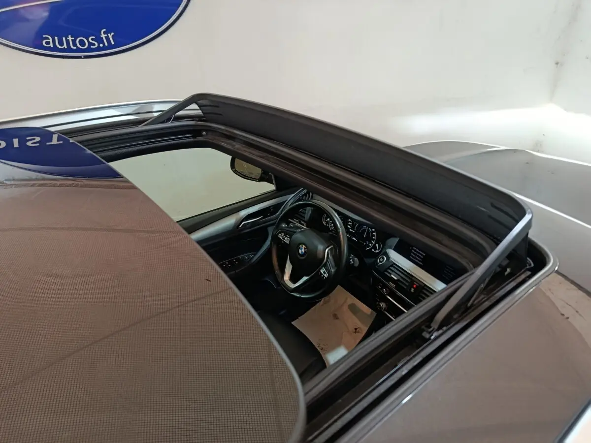 Vue plongeante sur l'intérieur gris foncé d'une BMW X3 xDrive30e 2020 avec toit ouvrant panoramique ouvert.