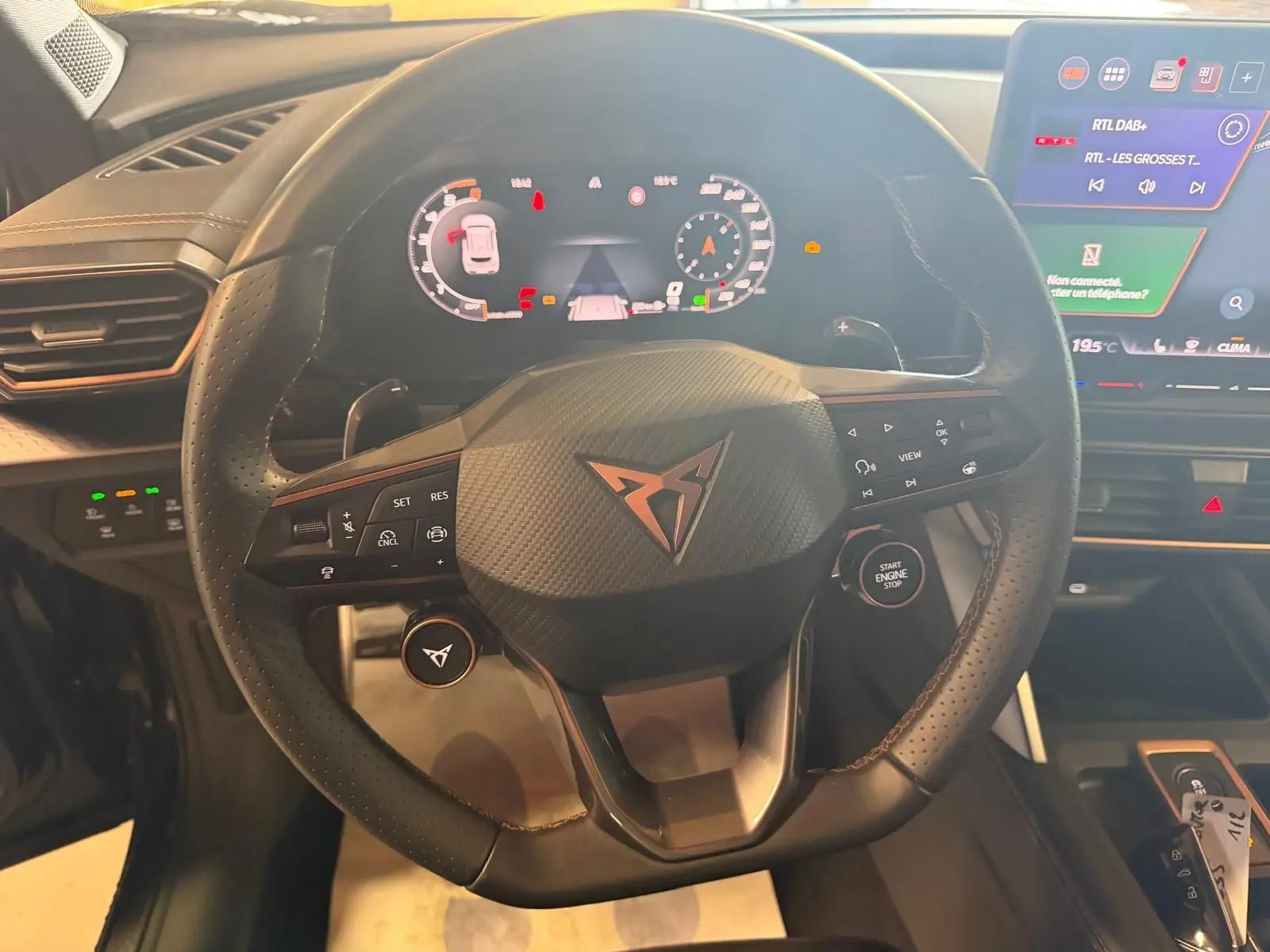 Vue intérieure centrée sur le volant cuir noir perforé de la CUPRA Formentor avec tableau de bord digital et écran tactile.