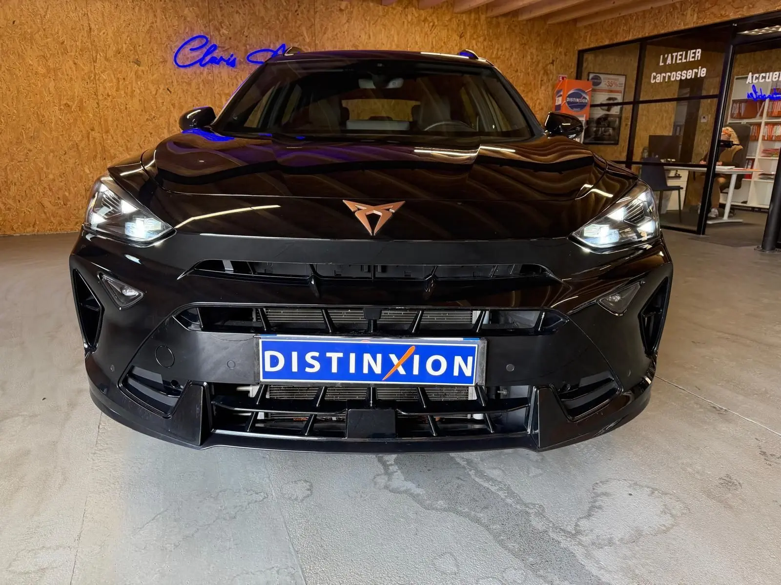 Vue frontale d'un CUPRA Formentor noir 2025 avec phares allumés et logo cuivré sur calandre sportive.