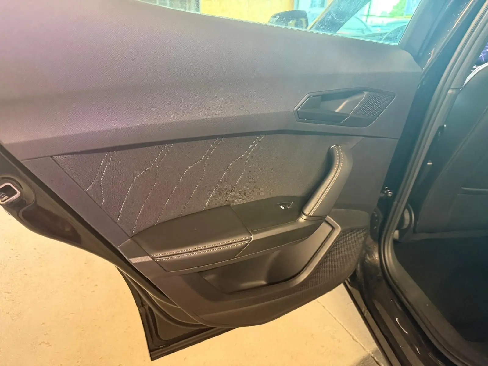 Vue intérieure du panneau de porte arrière gauche noir avec surpiqûres blanches sur un CUPRA Formentor 2025.